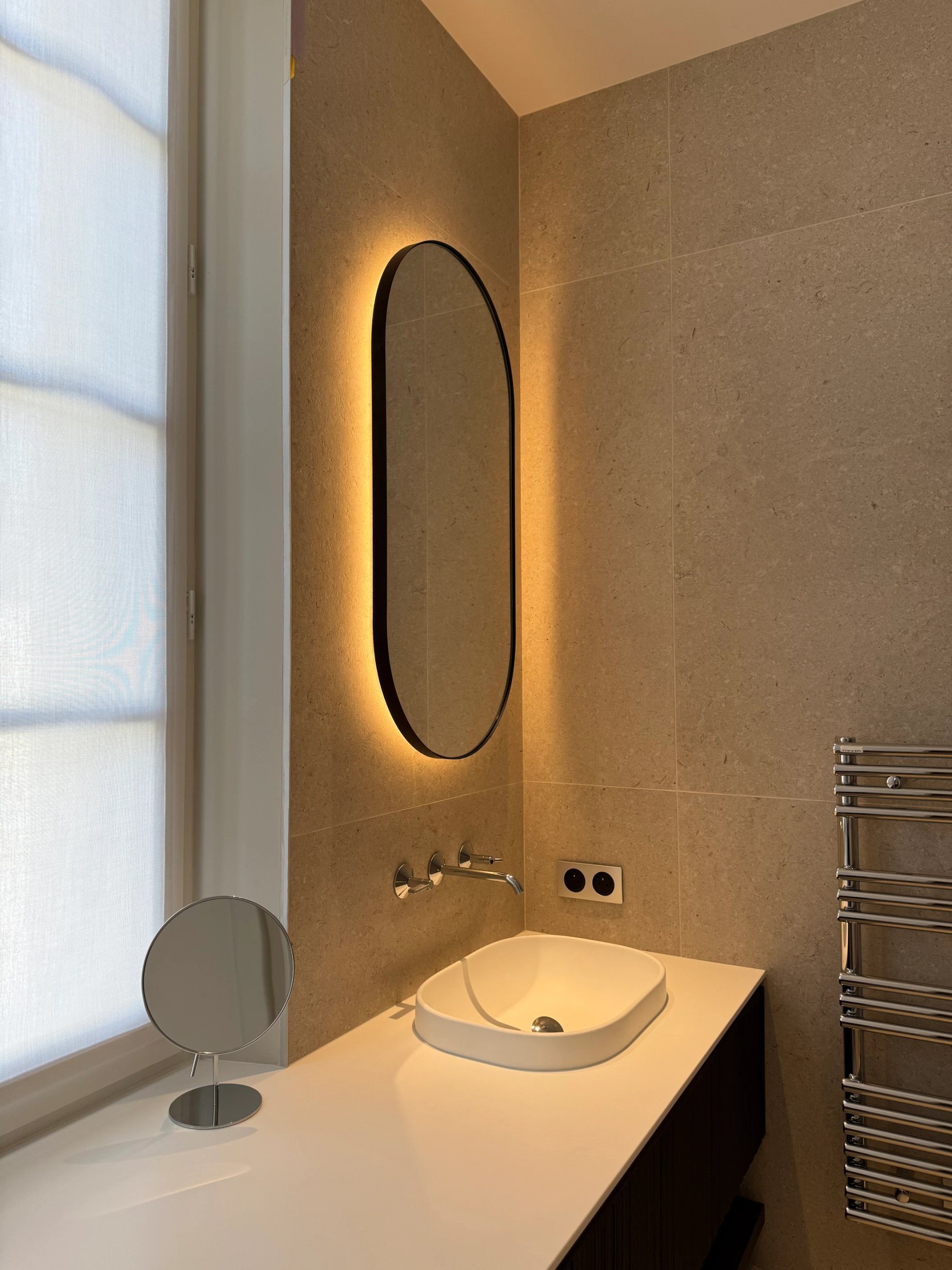 Salle de bain moderne avec miroir ovale dans la Chambre Essentielle de la Villa des Vignes