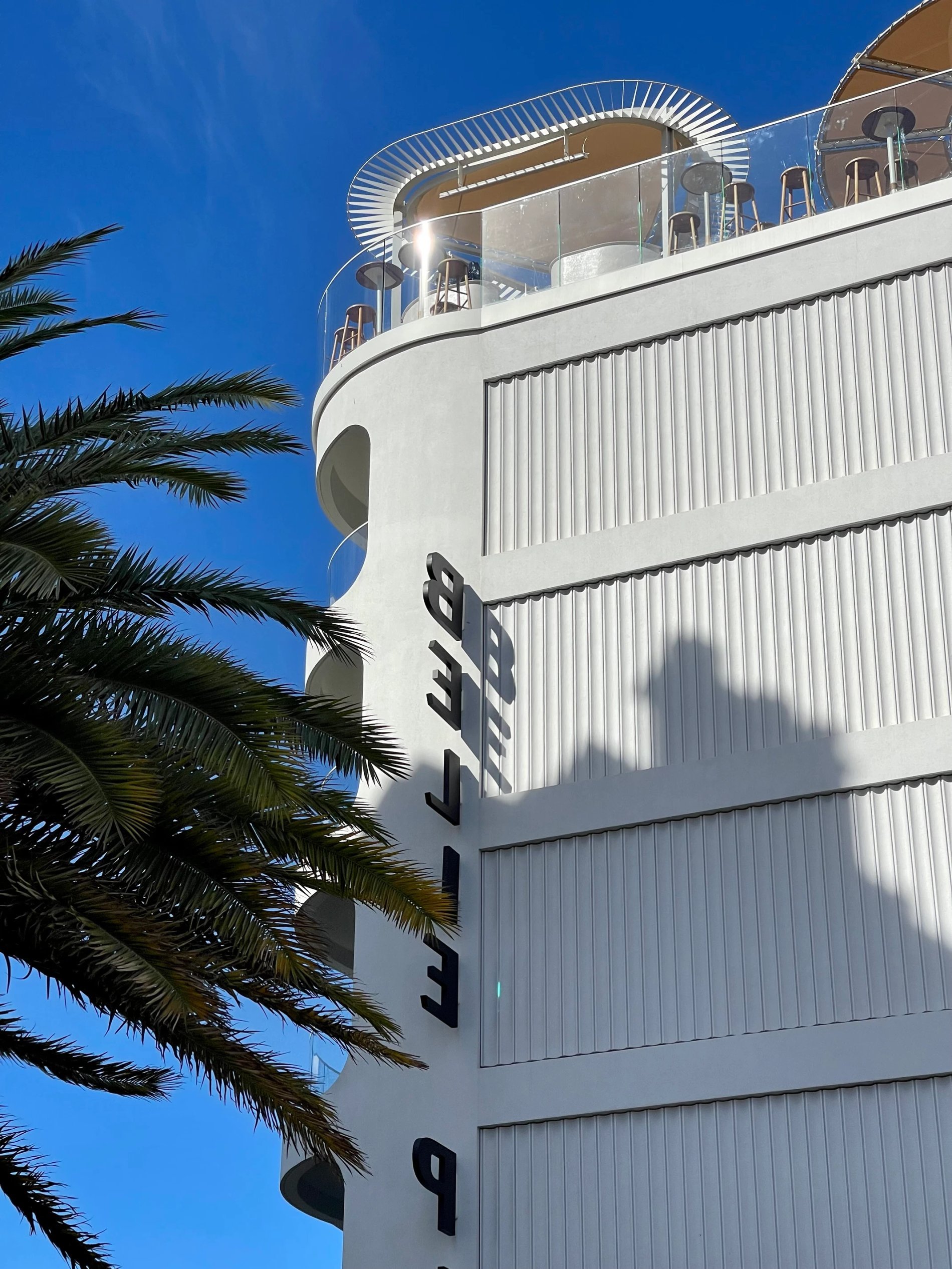 White front of Hôtel Belle Plage with rooftop and palm trees