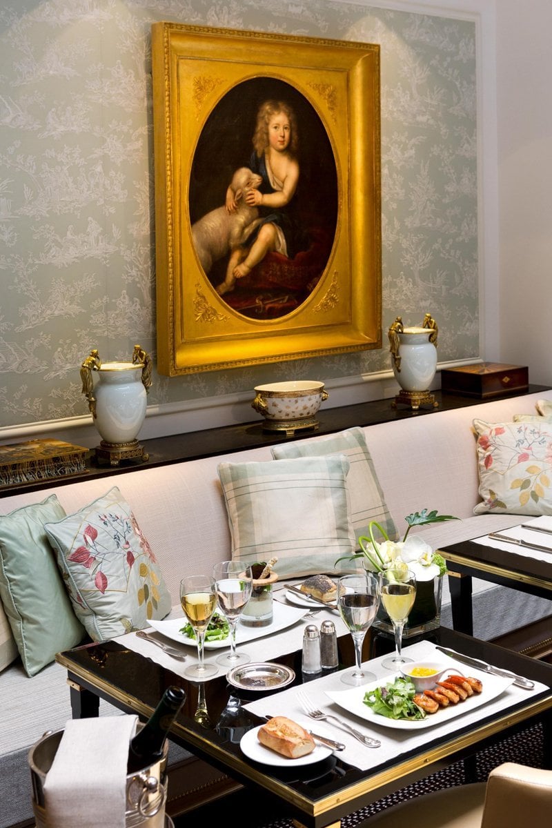 Table élégamment dressée pour un déjeuner raffiné à l’Hôtel San Régis Paris, sous un tableau ancien.