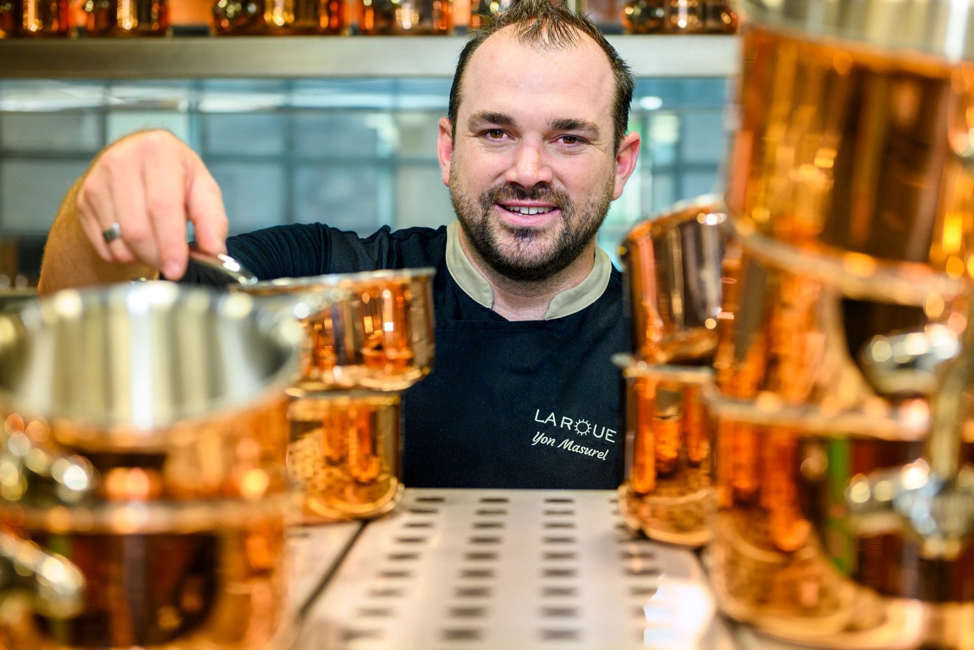 Portrait du chef devant des casseroles en cuivre dans le restaurant La Roue.