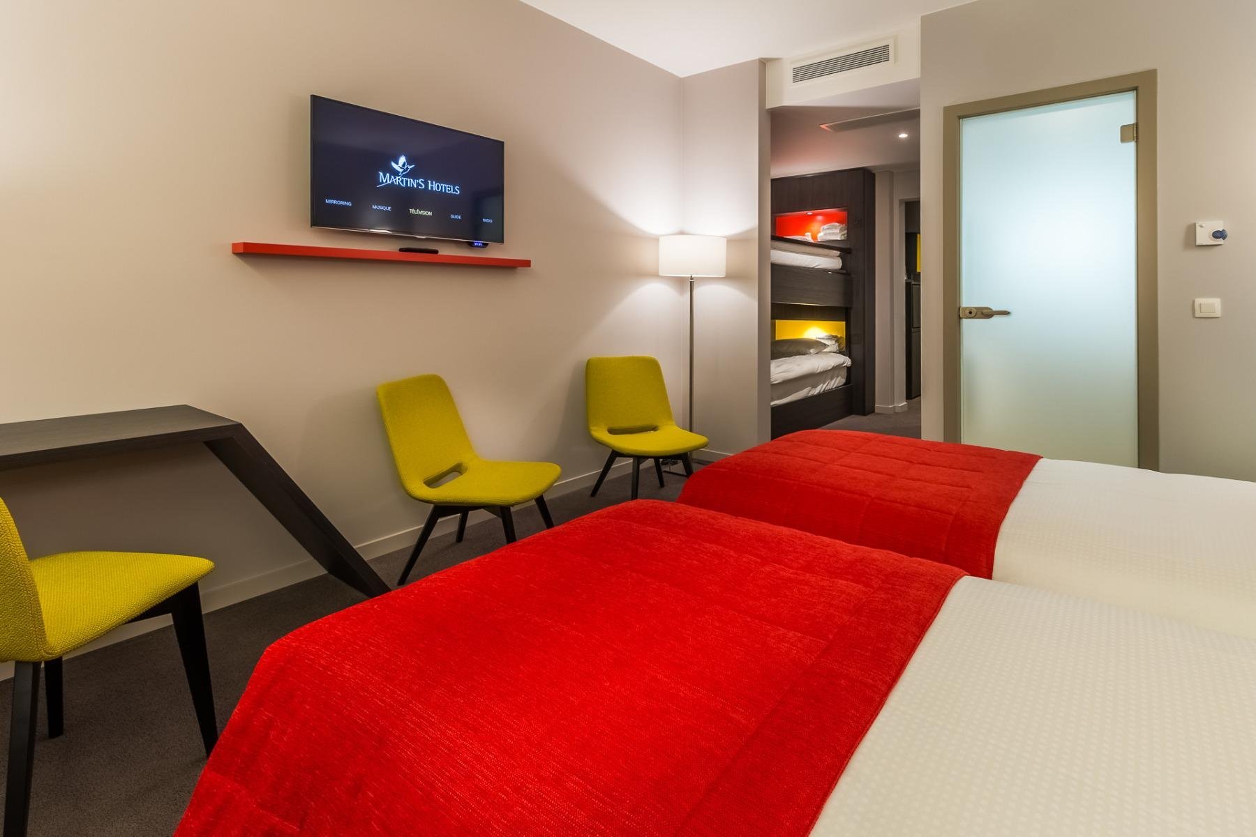 Charming Quadruple room at Martin's Red with bunk beds, red sofa, and modern decor.