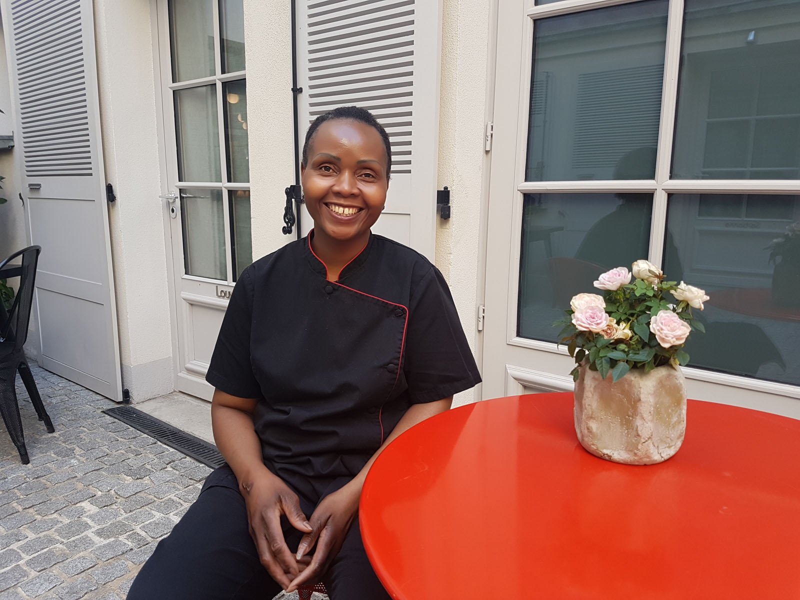 Chef souriant assis à une table rouge sur la terrasse de l'Hôtel Saint Dominique à Paris