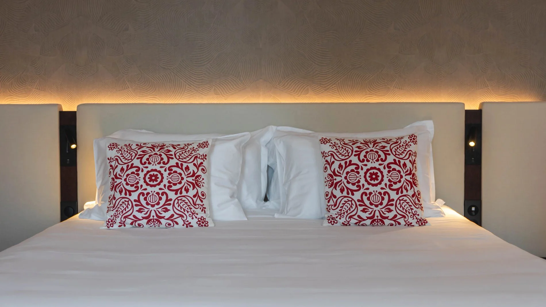 Lit double avec coussins rouges dans la Suite Signature de la Villa des Vignes à Saint-Émilion