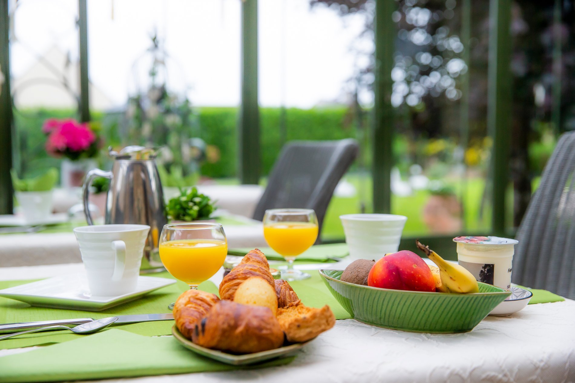 Petit-déjeuner complet avec viennoiseries, fruits et boissons sur table de l'Hôtel La Ramade, symbolisant un repas copieux.