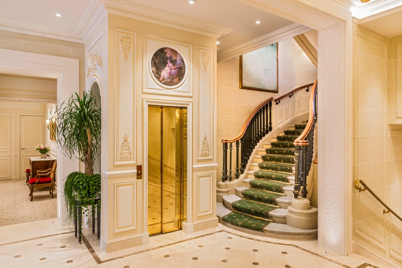 Golden elevator and green-carpeted staircase at Hôtel San Régis, a 5-star Paris hotel.