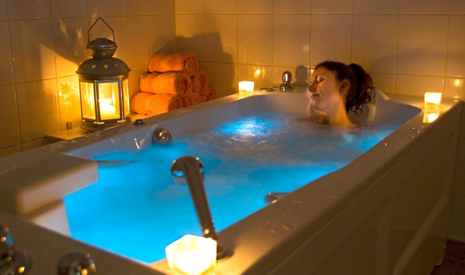 Personne se relaxant dans une baignoire éclairée par des bougies