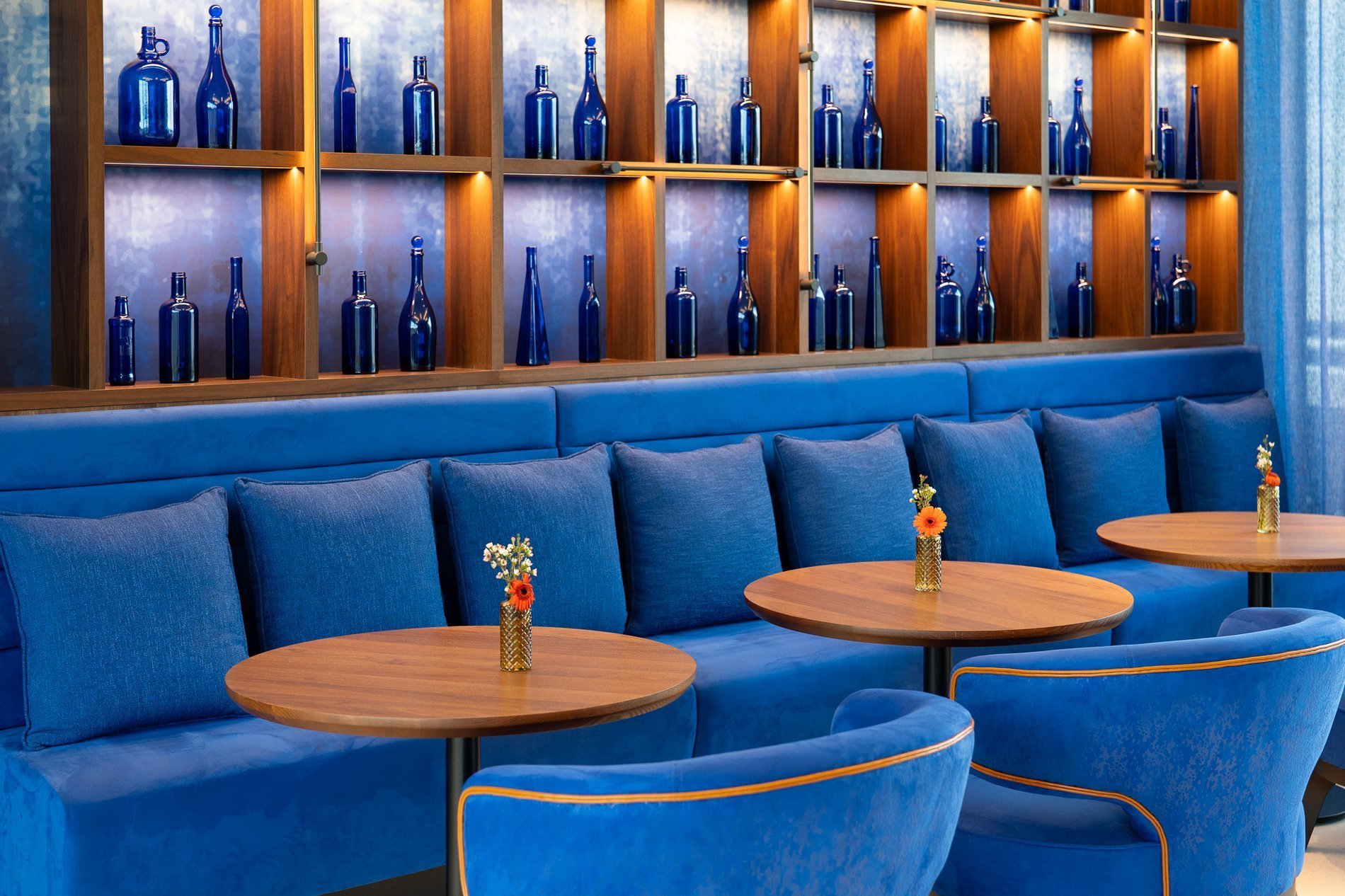 Bar bleu marine : étagères de bouteilles, fauteuils cosy, tables.