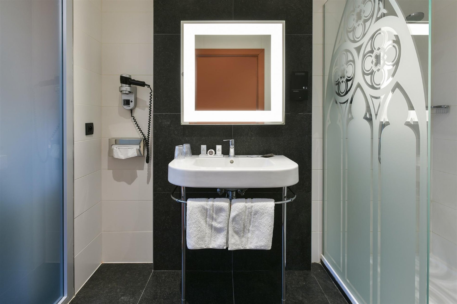 Modernes Badezimmer mit Dusche und beleuchtetem Spiegel.