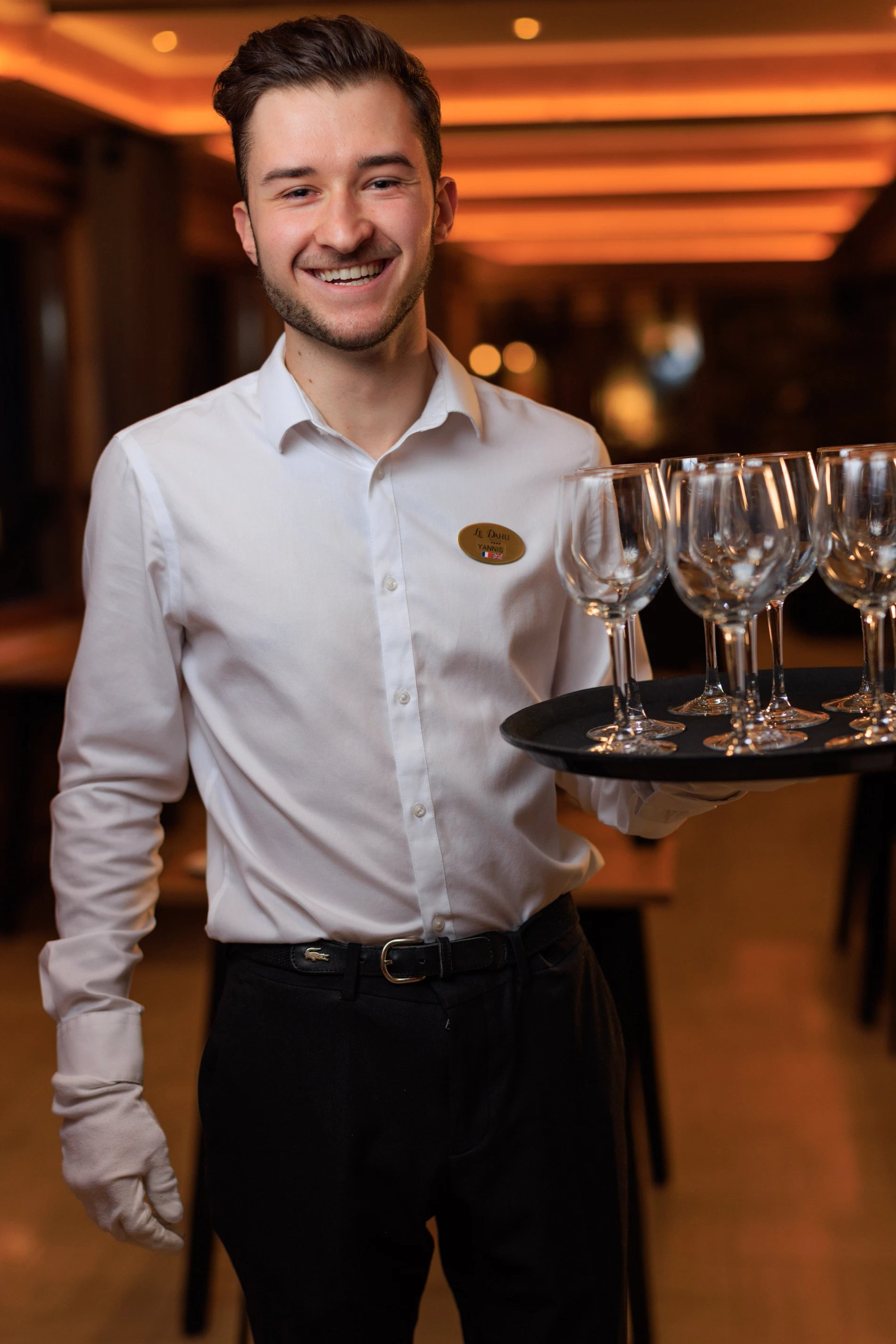 Yannis qui arbore un grand sourire alors qu'il est en train de dresser la salle de restaurant pour le soir