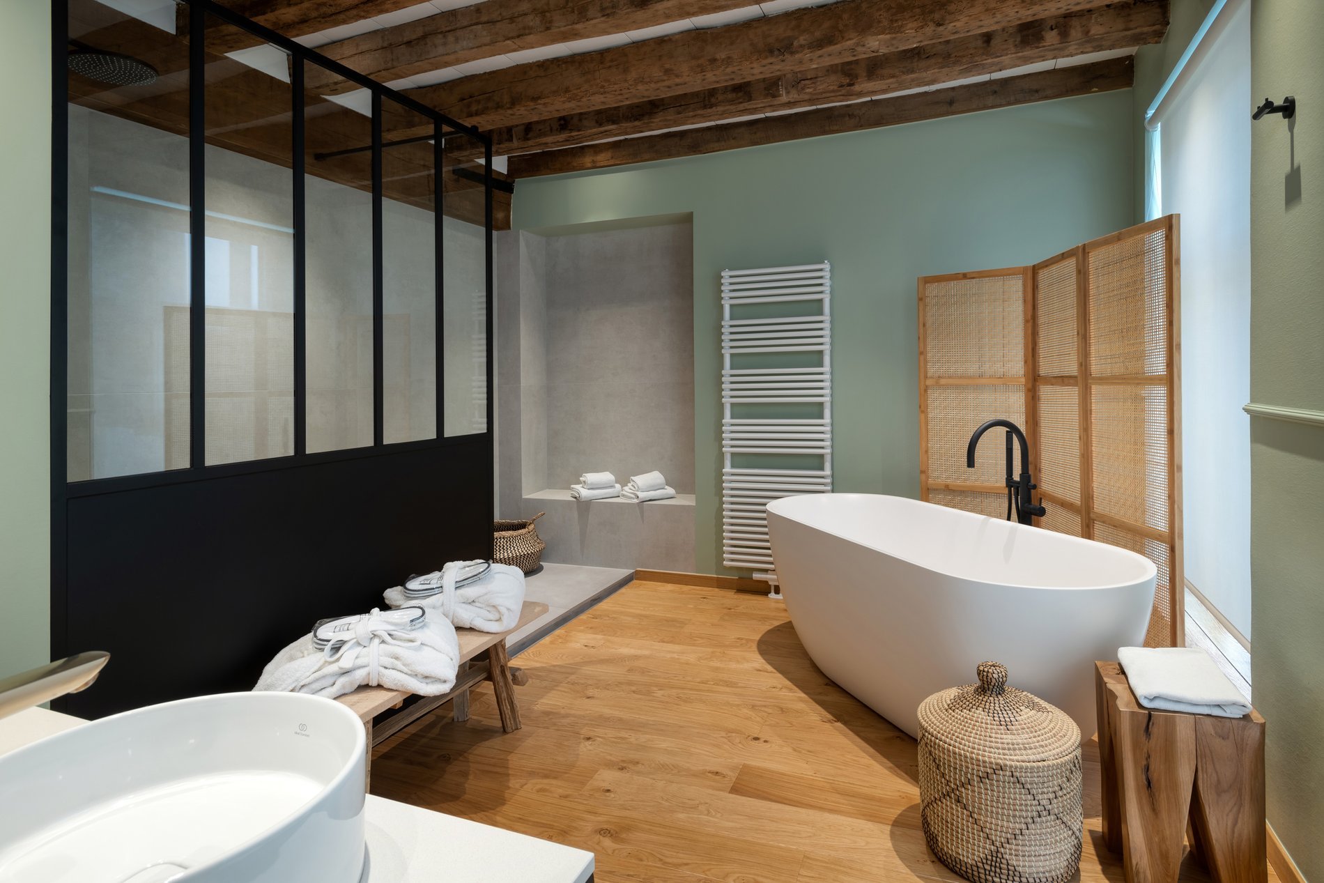 Salle de bain design avec baignoire îlot et poutres apparentes à Martin’s Relais.