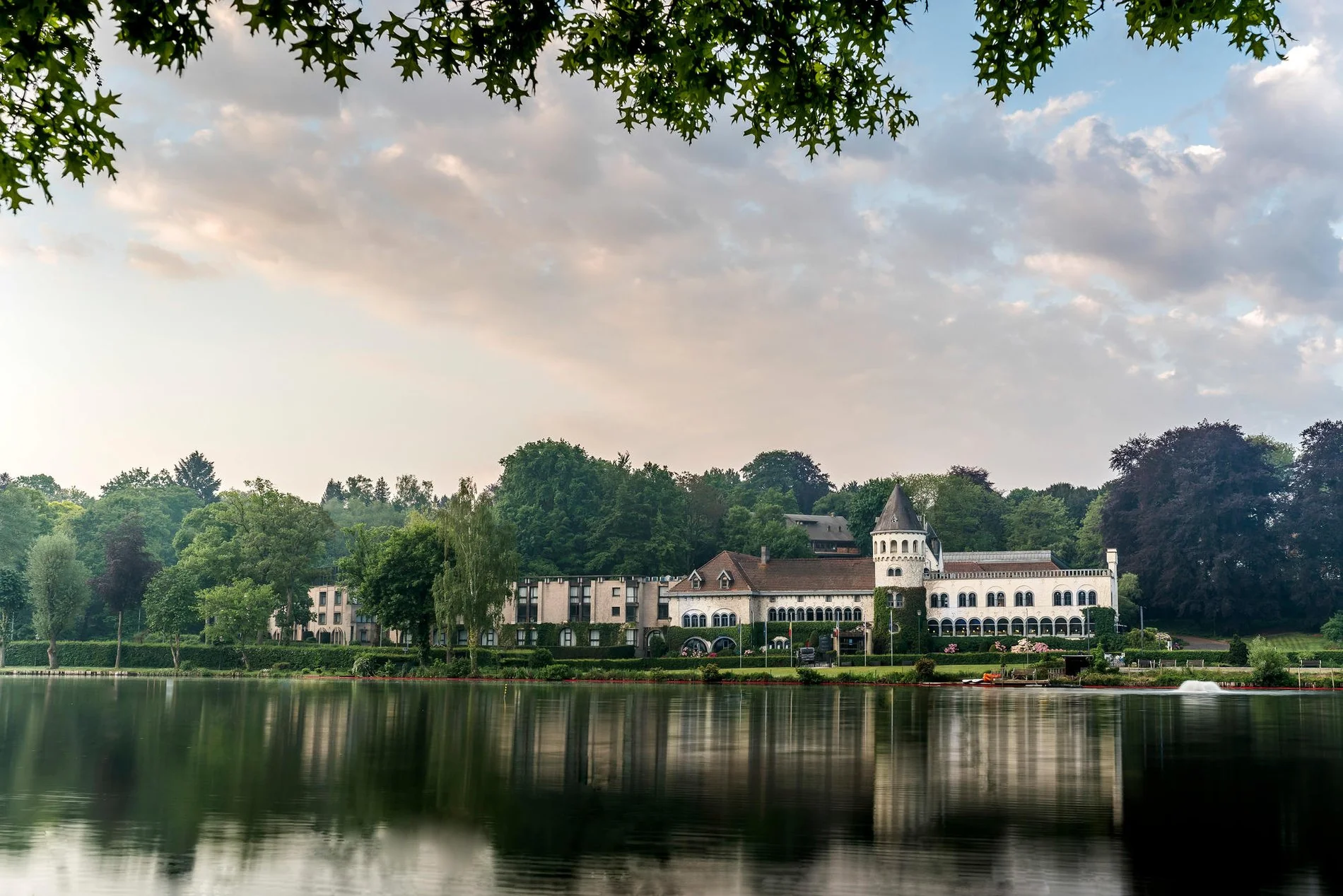 Panoramablick auf Martin's Château du Lac am See, umgeben von Grünflächen.