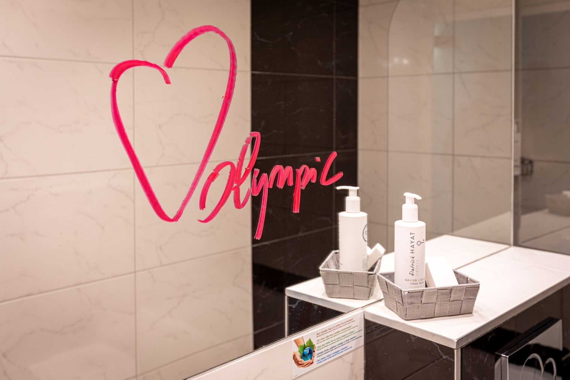 Détail de la salle de bain de la Chambre Classique Twin Olympic avec produits d’accueil et miroir design.