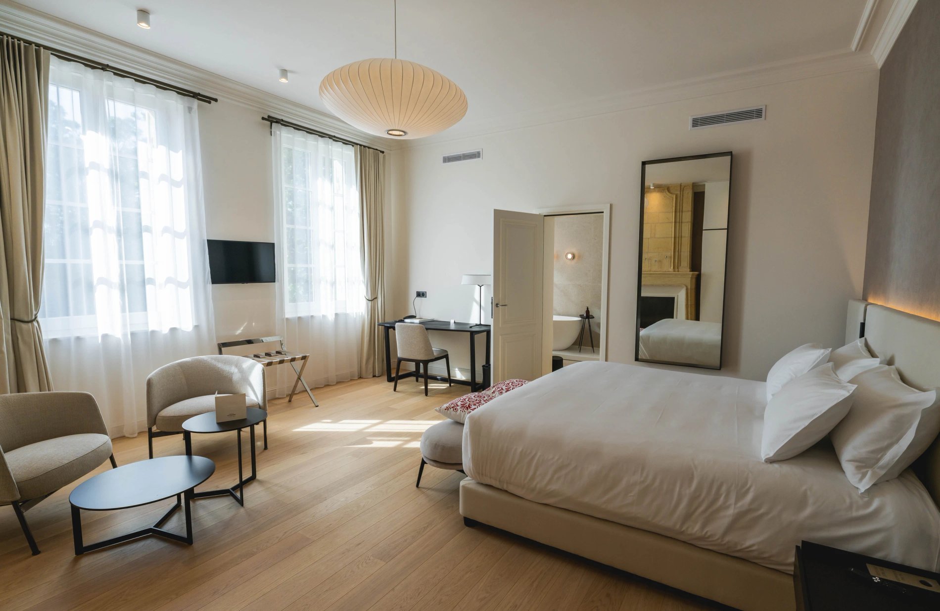 Chambre lumineuse avec coin salon dans la Suite Signature de la Villa des Vignes