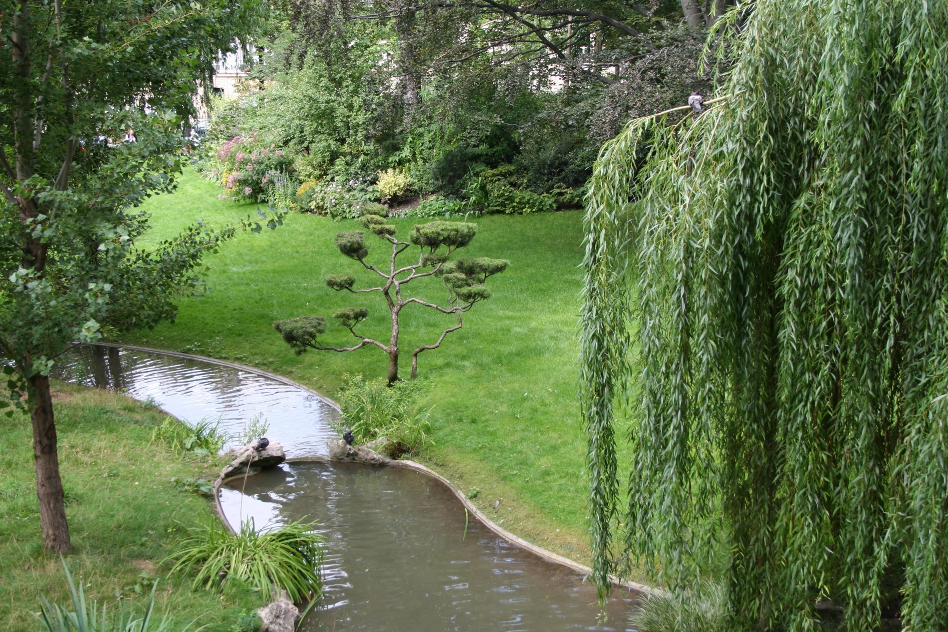 Square des Batignolles à Paris avec rivière, saules pleureurs et espaces verts à proximité de l’Hôtel Glasgow Monceau