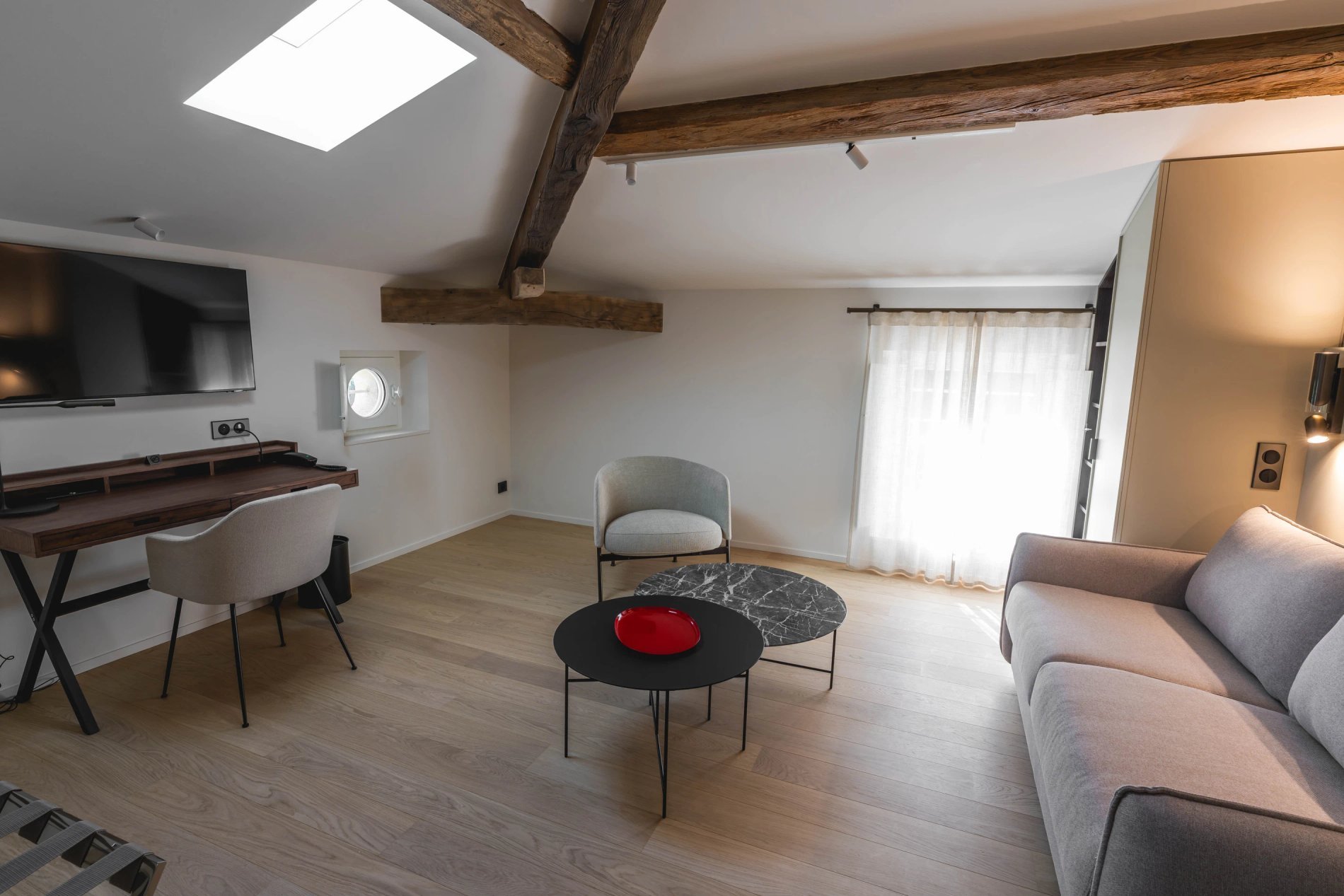 Salon chaleureux avec canapé et poutres apparentes dans la Suite Prestige de la Villa des Vignes