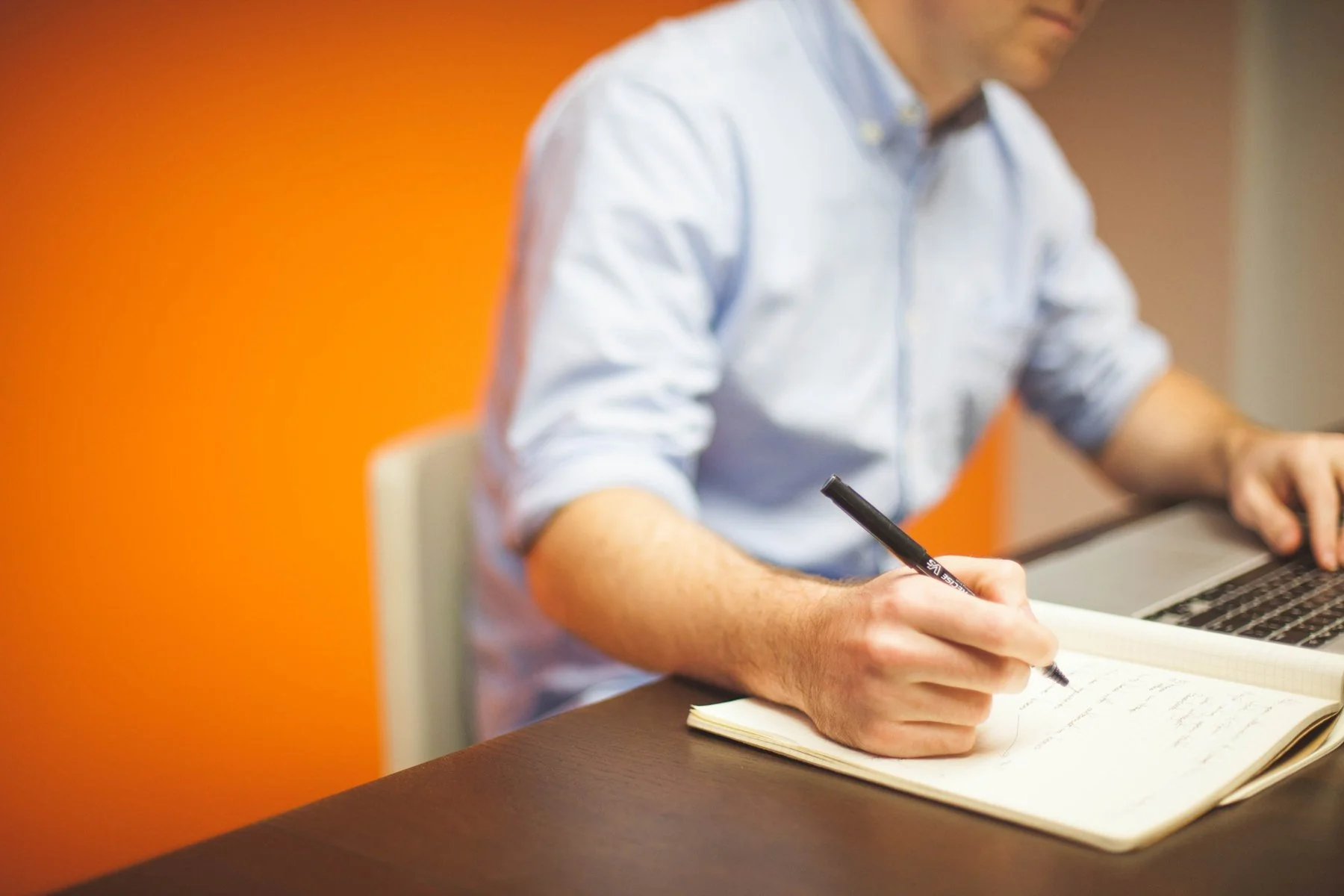 Man in shirt taking notes at his desk, reflecting a studious mindset and a professional setting.