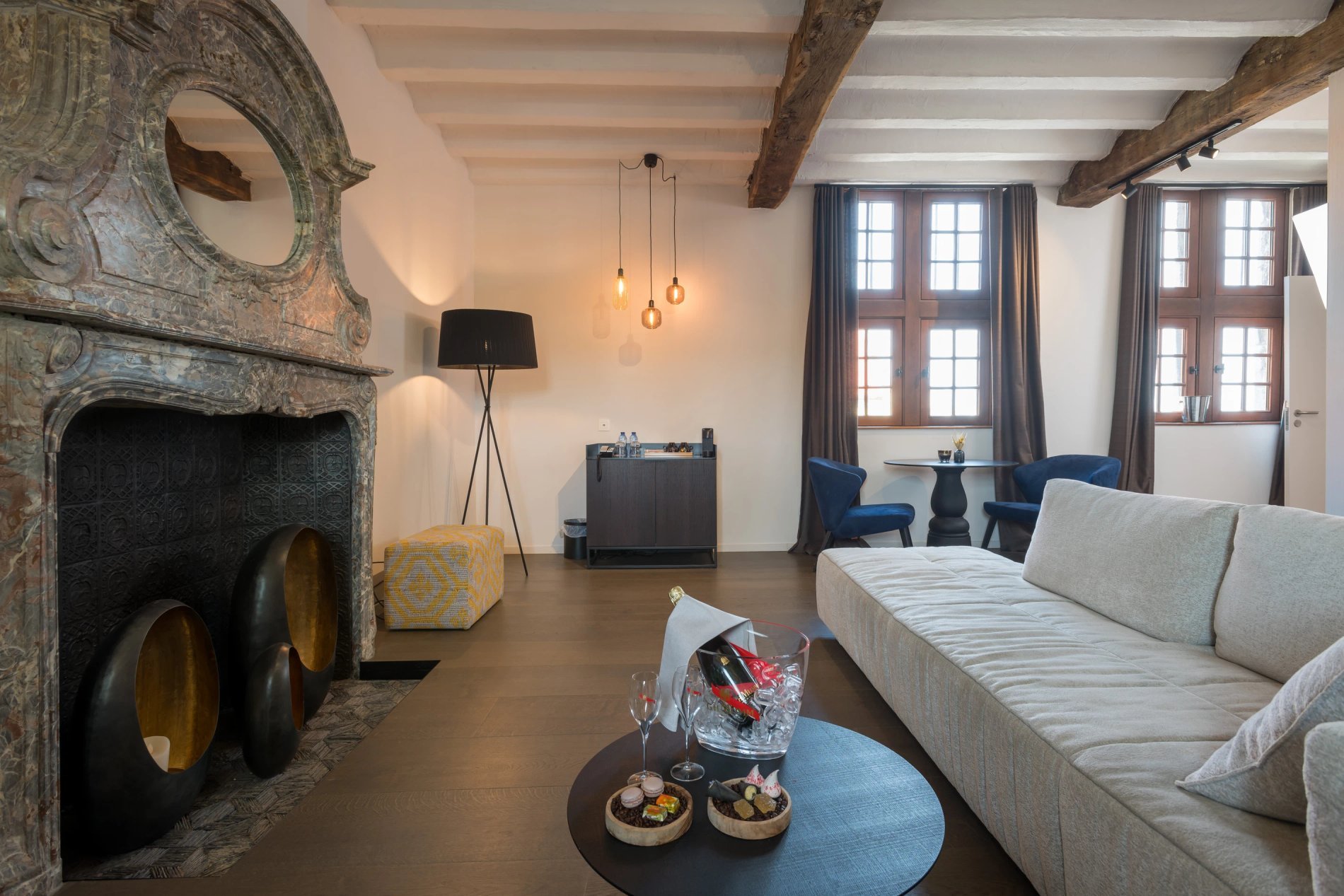 Gezellige lounge met open haard en zichtbare balken in het Martin's Rentmeesterij in Bilzen.