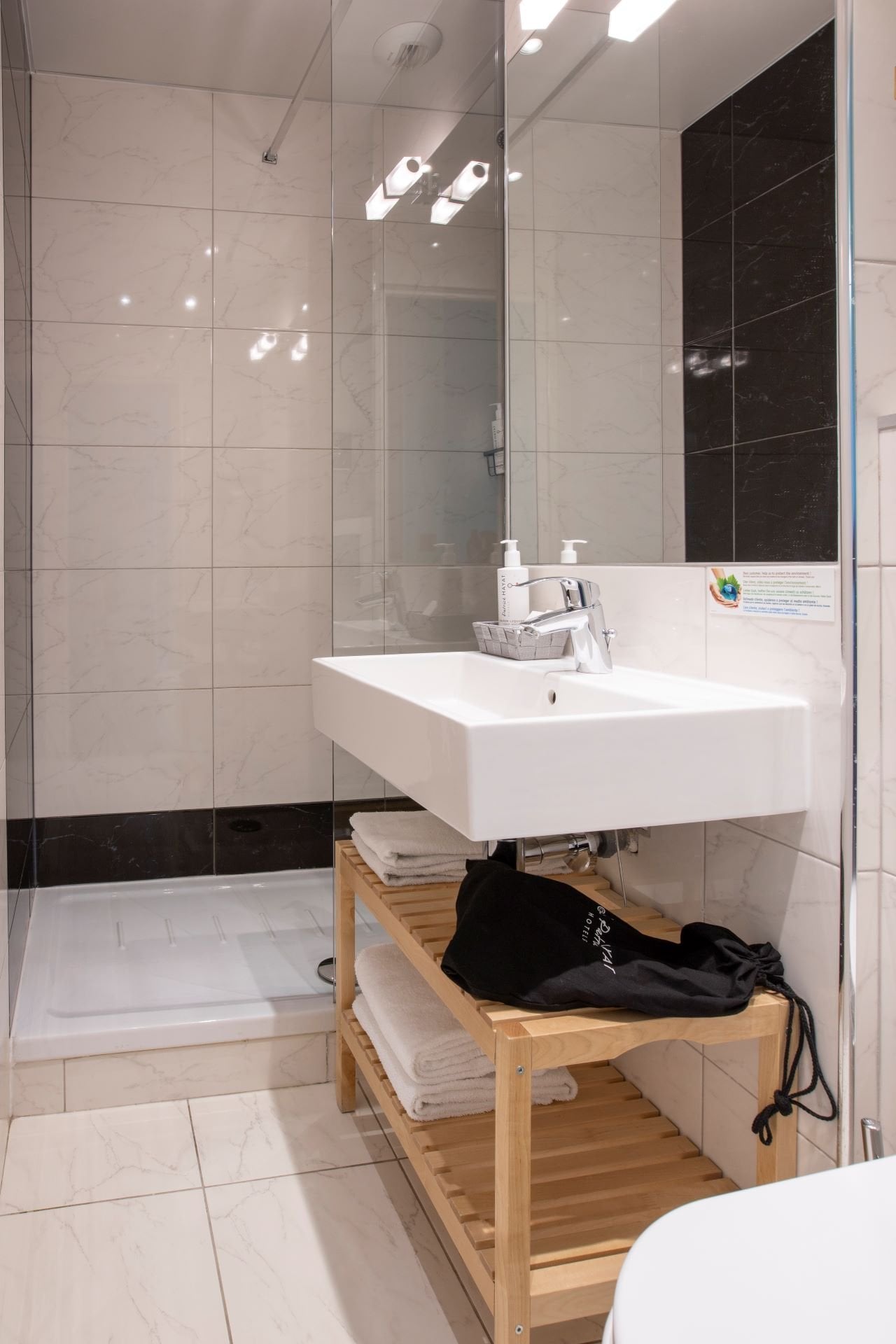 Salle de bain privative de la Chambre Grand Chelem Supérieure de l’Hôtel Olympic à Boulogne-Billancourt avec douche à l’italienne, lavabo moderne et équipements de qualité.