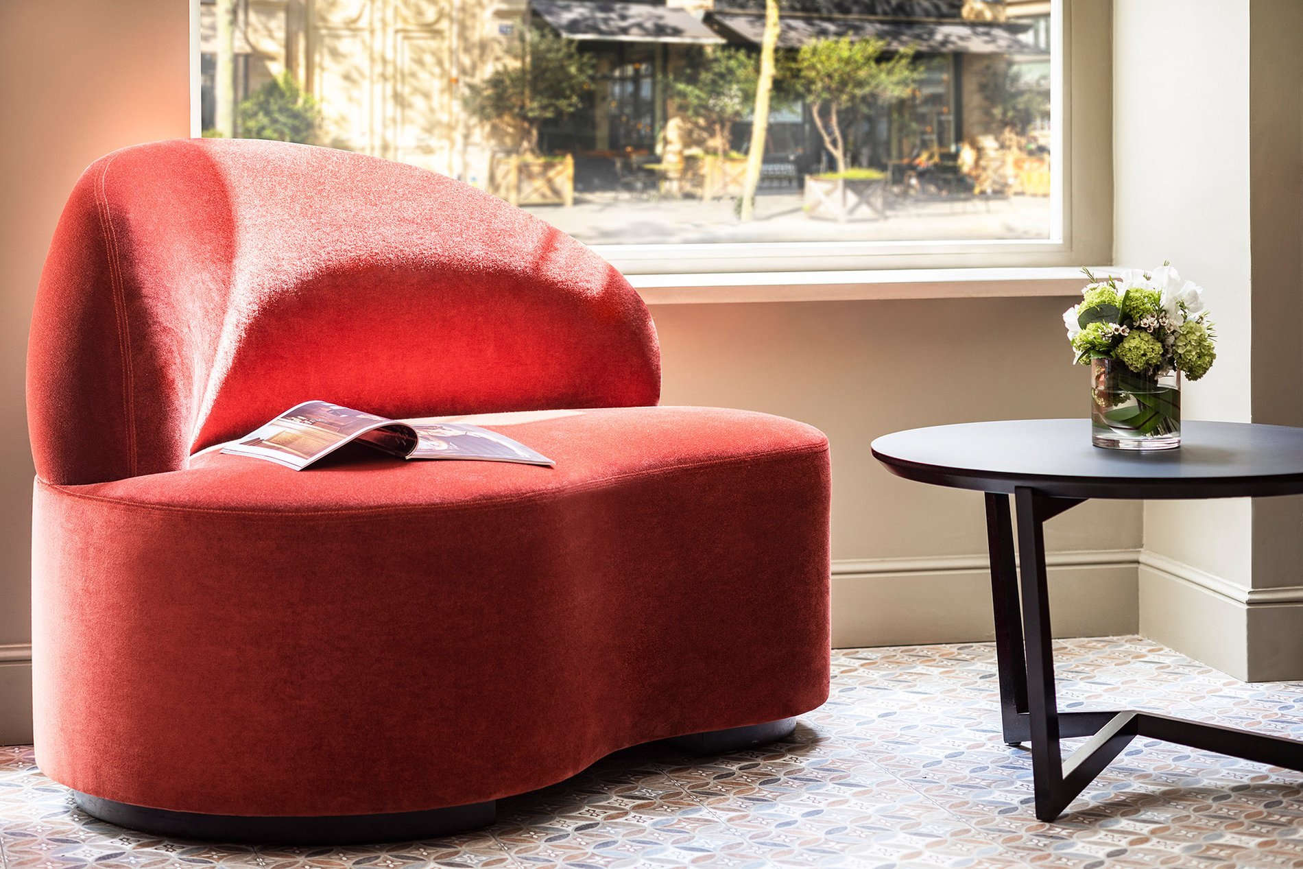Fauteuil design rouge dans le salon de l’Hôtel Ducs de Bourgogne, hôtel 4 étoiles Paris 1er