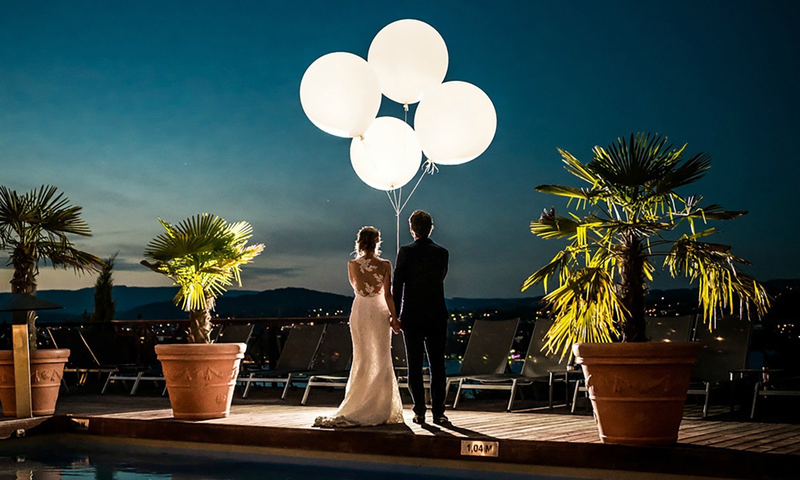 Ambiance féerique : couple de mariés lâchant des ballons lumineux dans la nuit à l'Hôtel Les Trésoms.