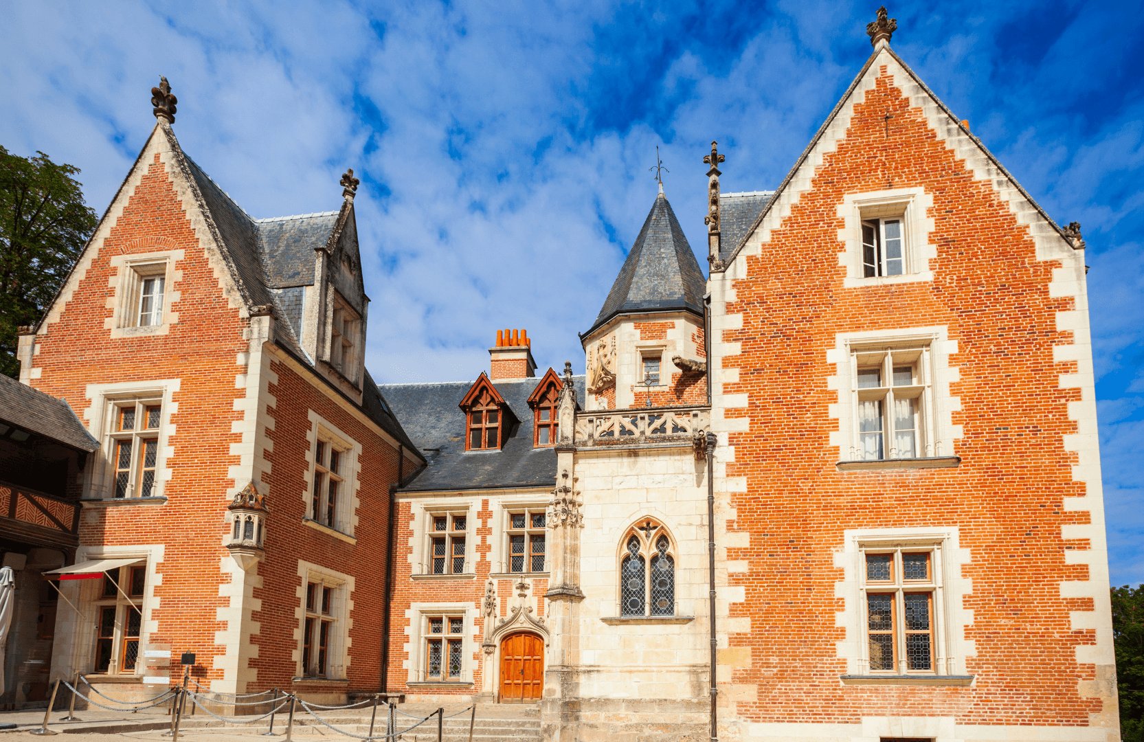 Façade d'un château historique à Chenonceaux avec des murs en briques rouges et des toits en ardoise.