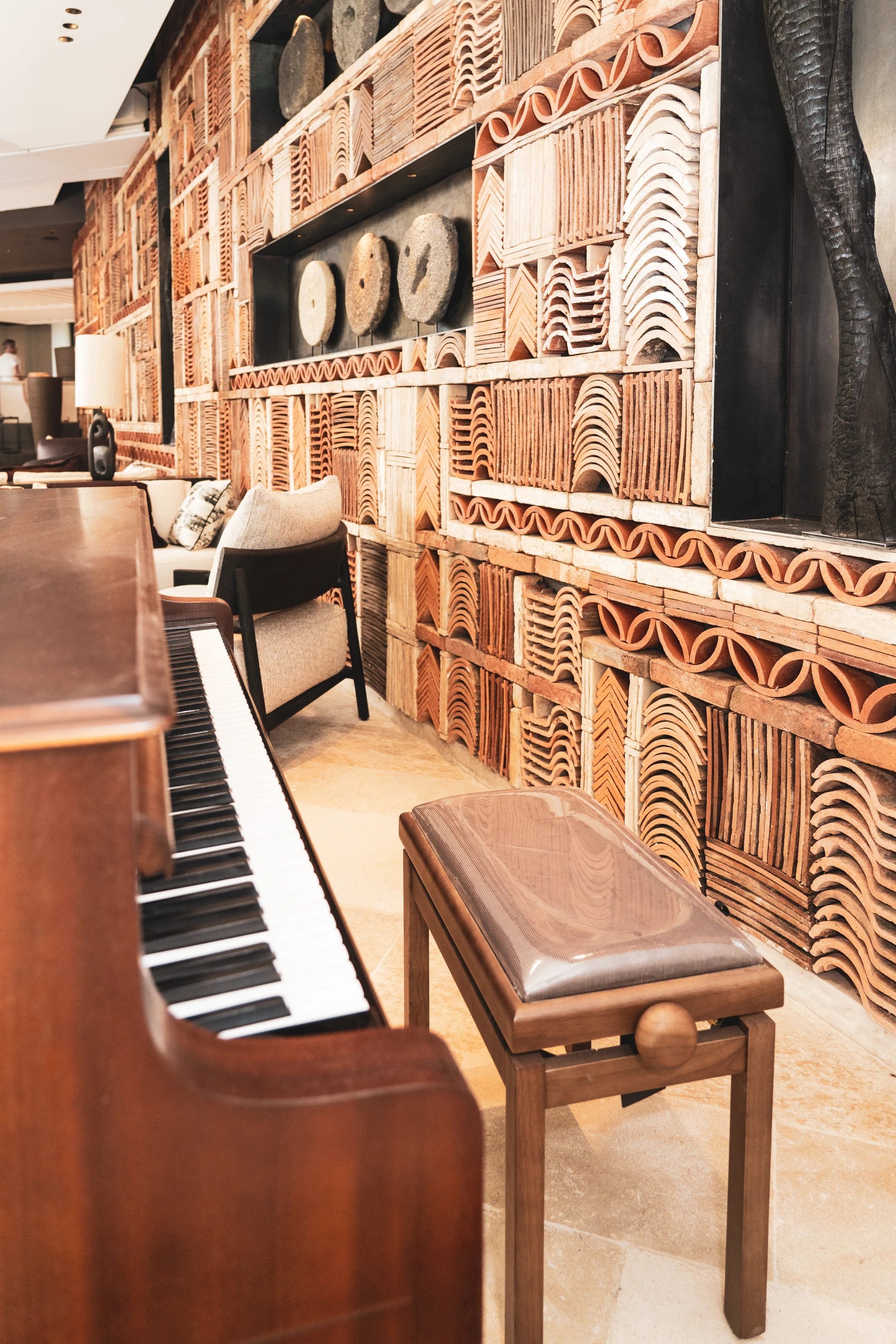 Mur de tuiles derrière un piano dans un salon de L’Isle de Leos.