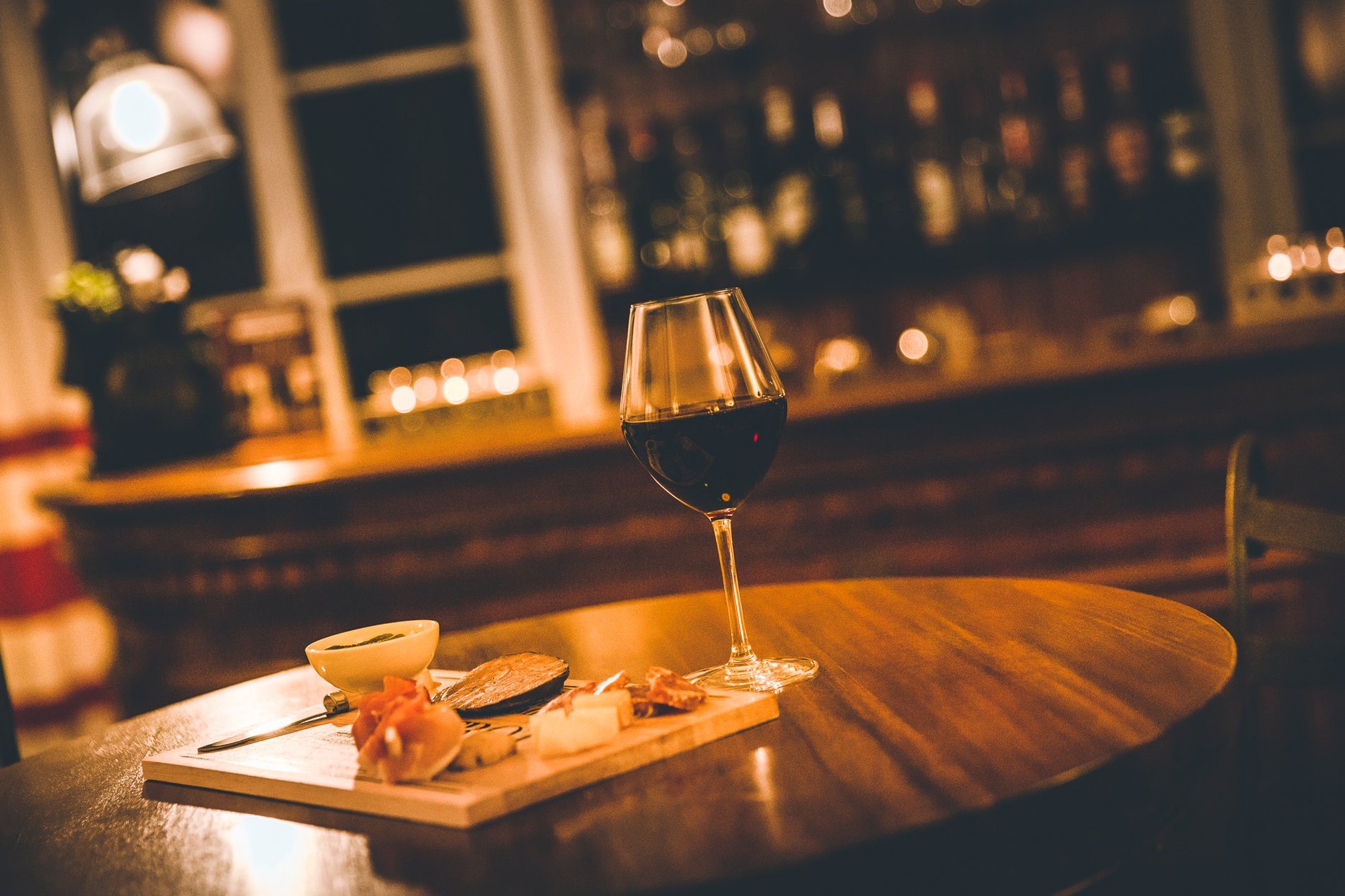 Verre de vin sur une table de bar de l'Hôtel La Ramade, symbolisant l'offre de boissons en soirée.