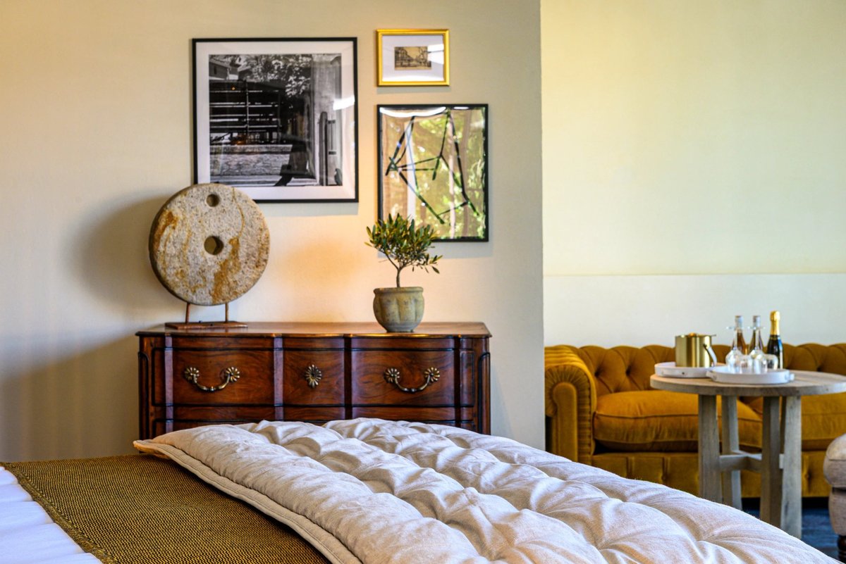 Isle de Leos, Chambre élégante avec commode ancienne, déco murale et coin salon à L’Isle de Leos.