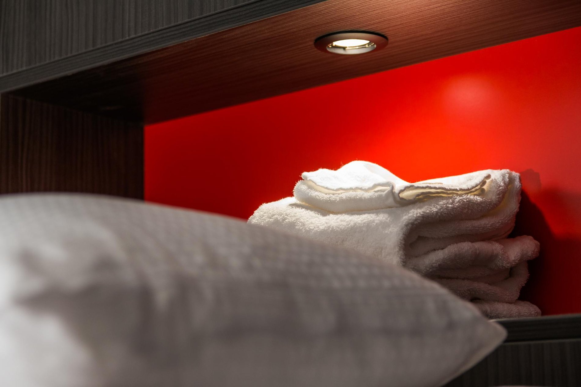 Bed in a room at Martin's Red with built-in lighting and vibrant red wall.