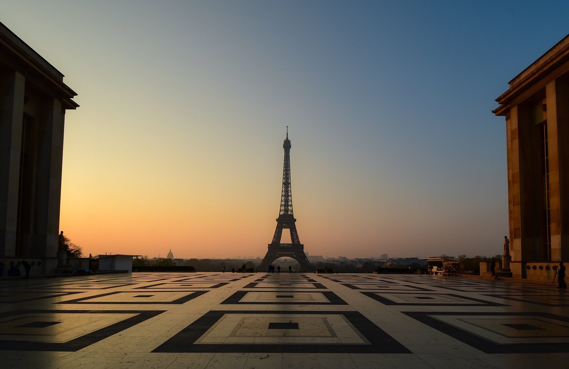 View of the Arc de Triomphe and the Eiffel Tower at sunset in Paris.