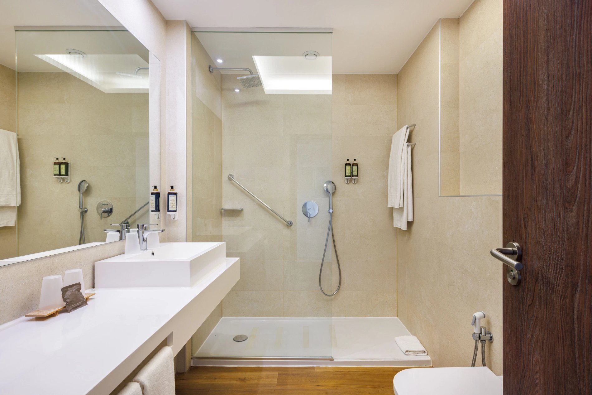 Salle de bain spacieuse avec douche, serviettes et articles de toilette au Jupiter Albufeira Hôtel