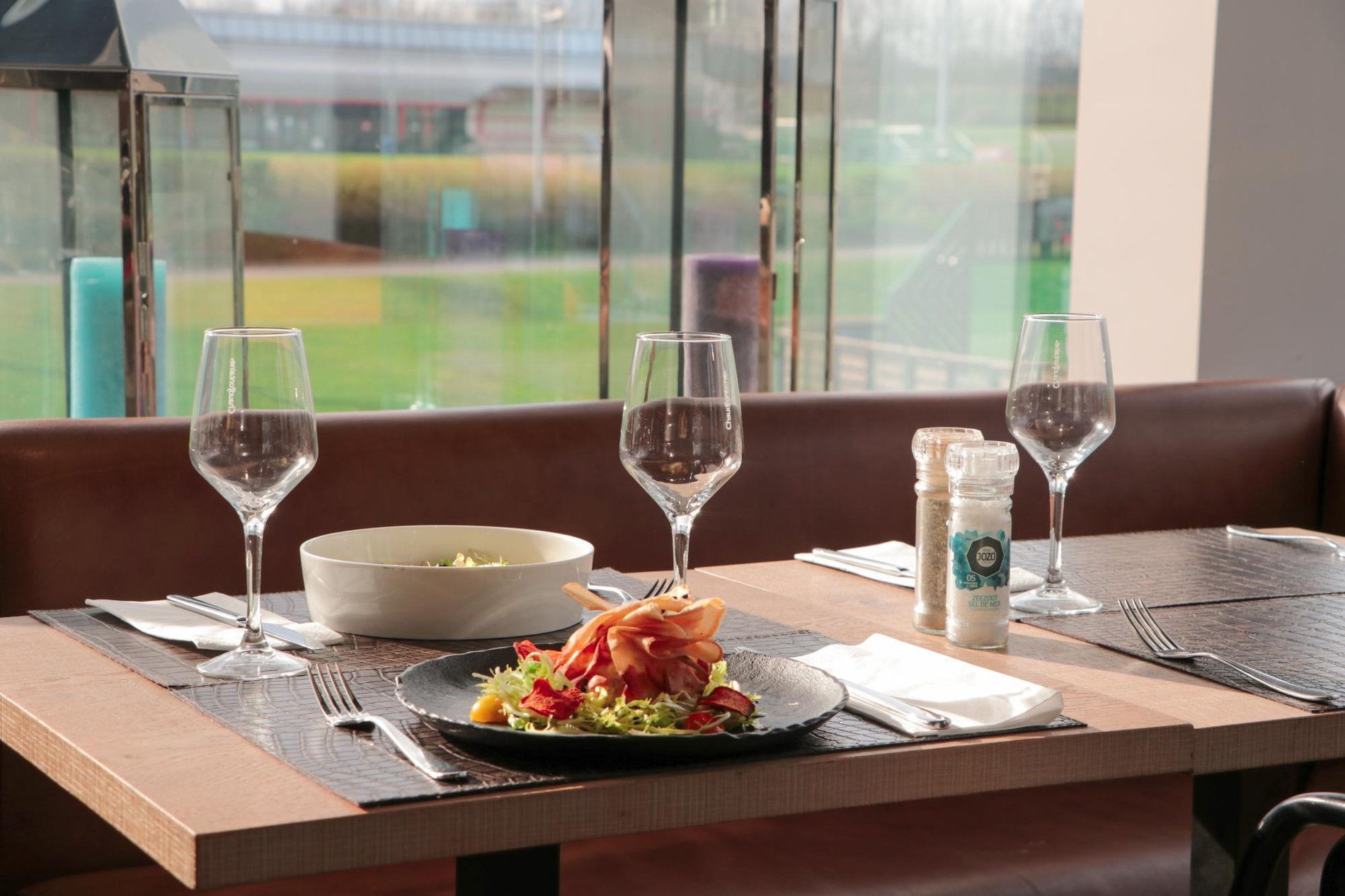 Elegantly set table with wine glasses and a plate of pasta, offering an outdoor view.