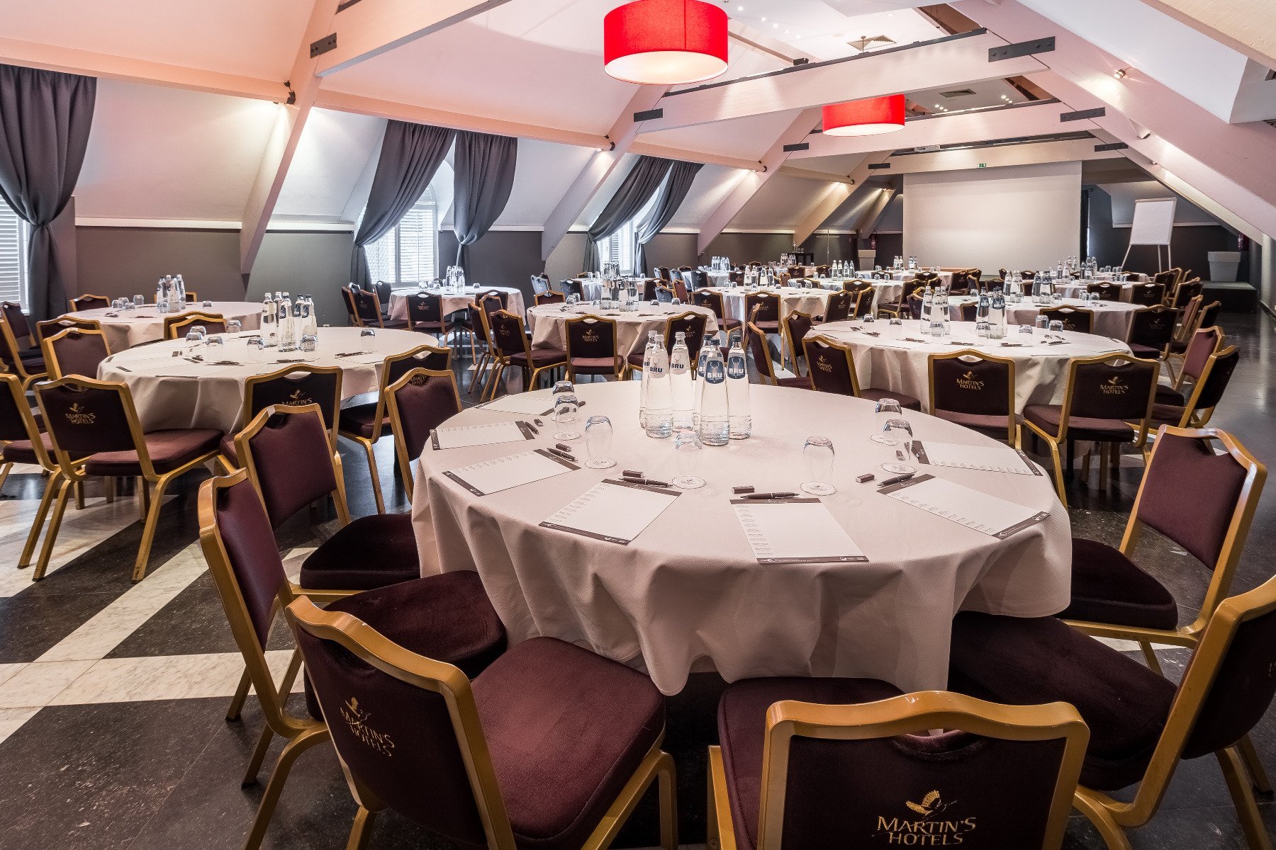 Reception hall with elegantly set round tables and bright ambiance at Martin's Château du Lac.