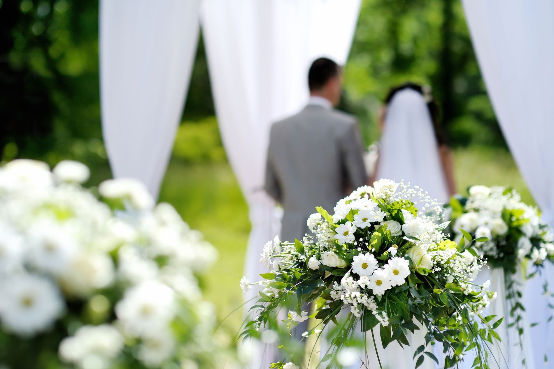 Outdoor wedding ceremony at Martin's Château du Lac with an arch decorated with white flowers.