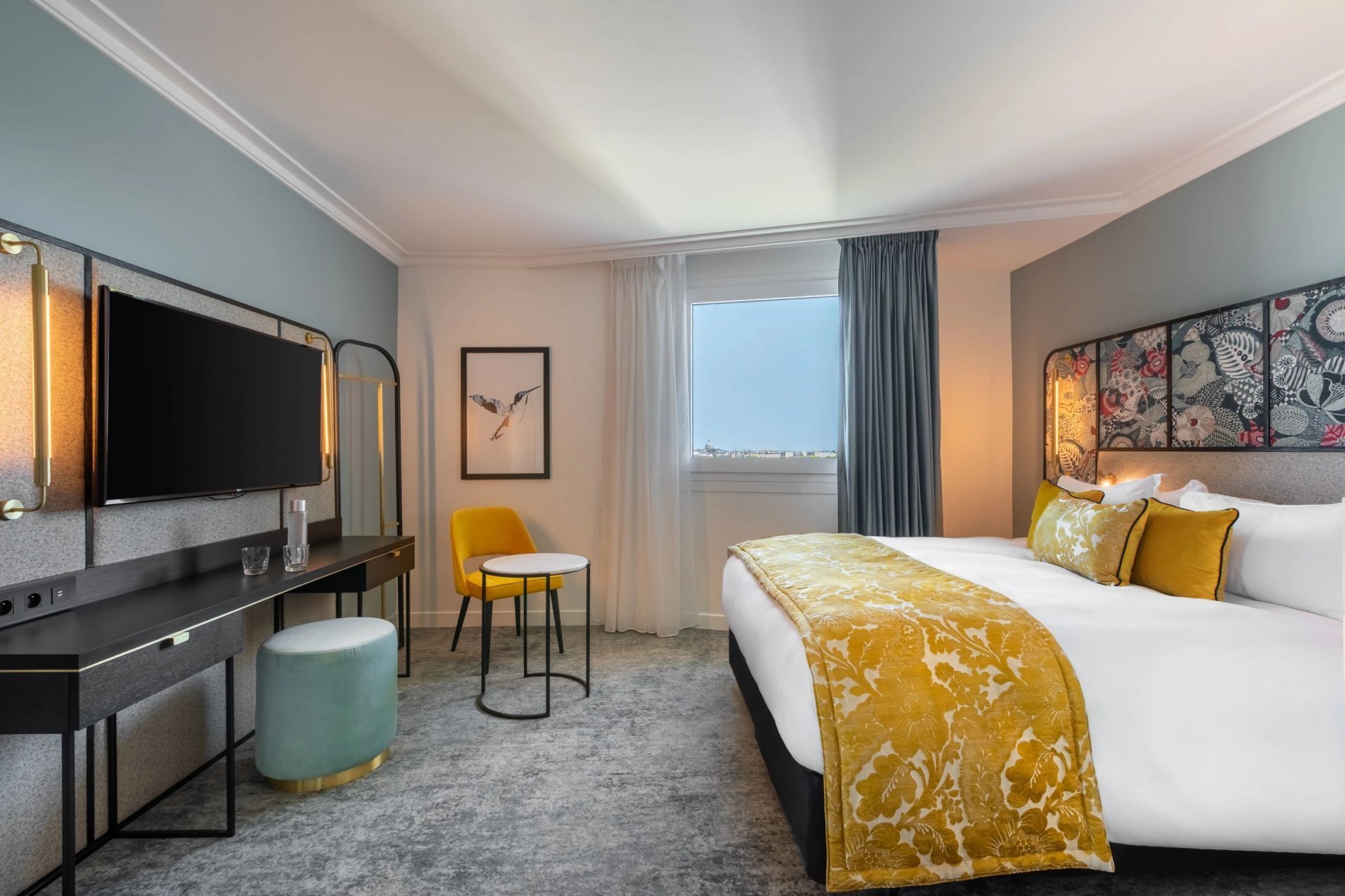 Decoration details of a Deluxe Room at VOCO Paris Montparnasse with a double bed, colorful cushions, and a bedside lamp.