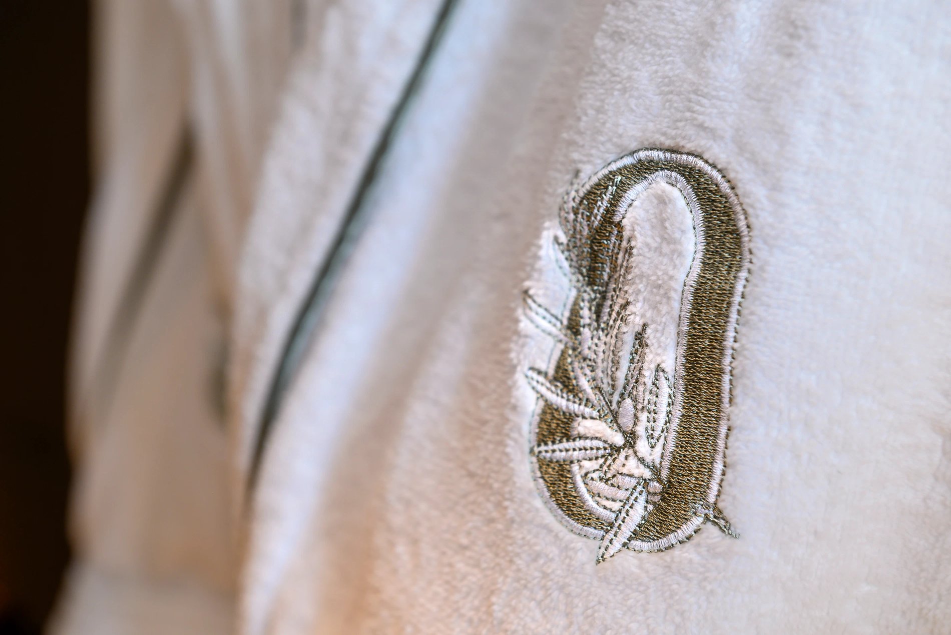 Peignoir blanc brodé du logo de L’Isle de Leos avec rameau d’olivier.