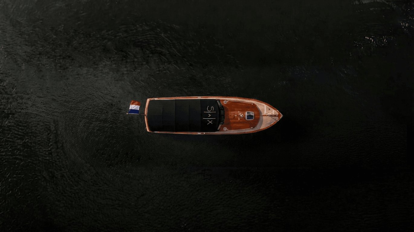 Yacht de luxe naviguant sur une étendue d'eau sombre avec un drapeau franco-néerlandais