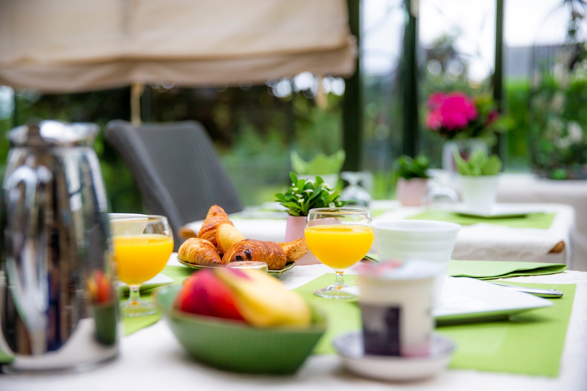 Détail de table de petit-déjeuner de l'Hôtel La Ramade avec tasses, jus et fruits, symbolisant la variété des produits.