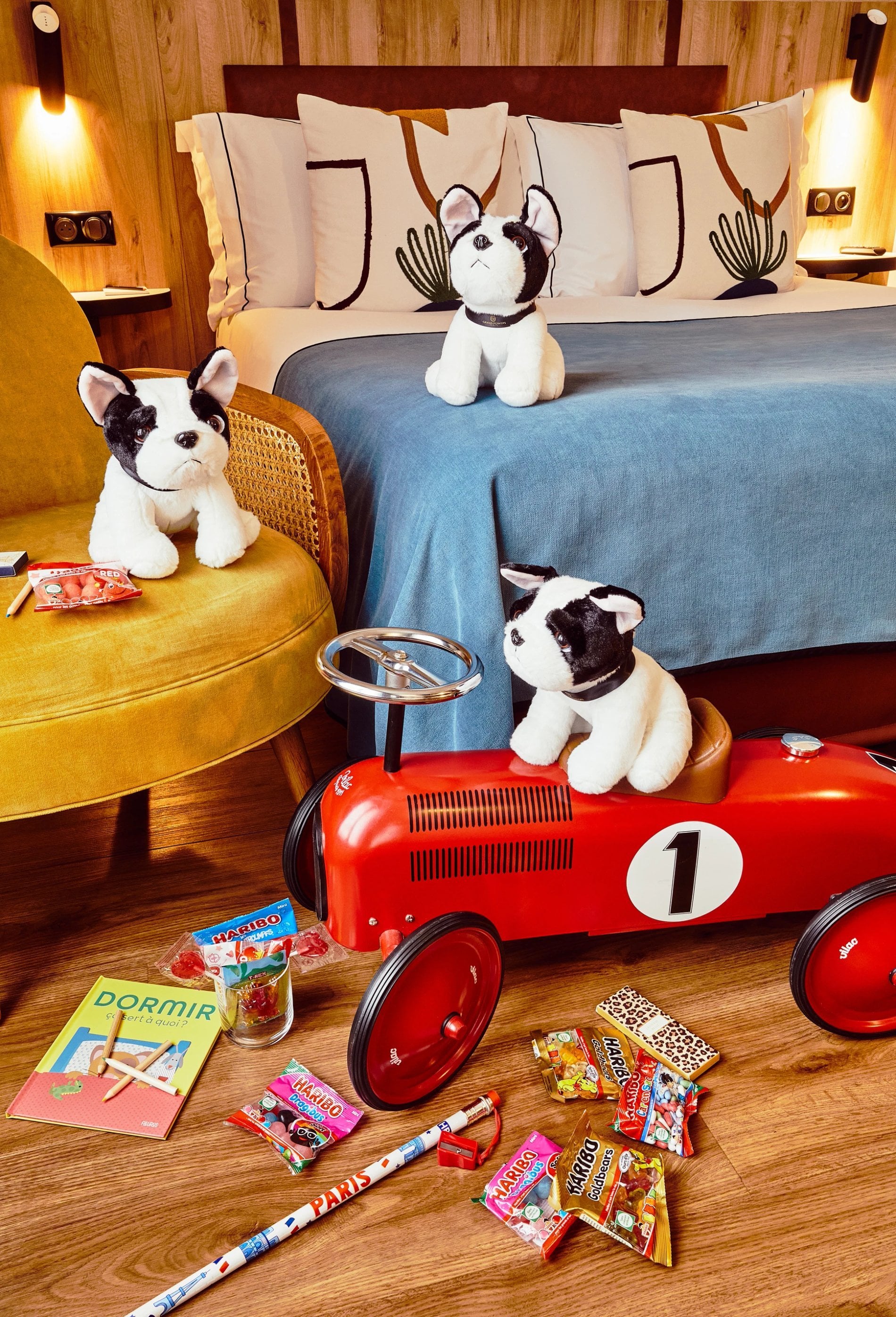 Chambre familiale du Plaza Tour Eiffel avec jouets pour enfants, voiture rétro rouge et peluches.