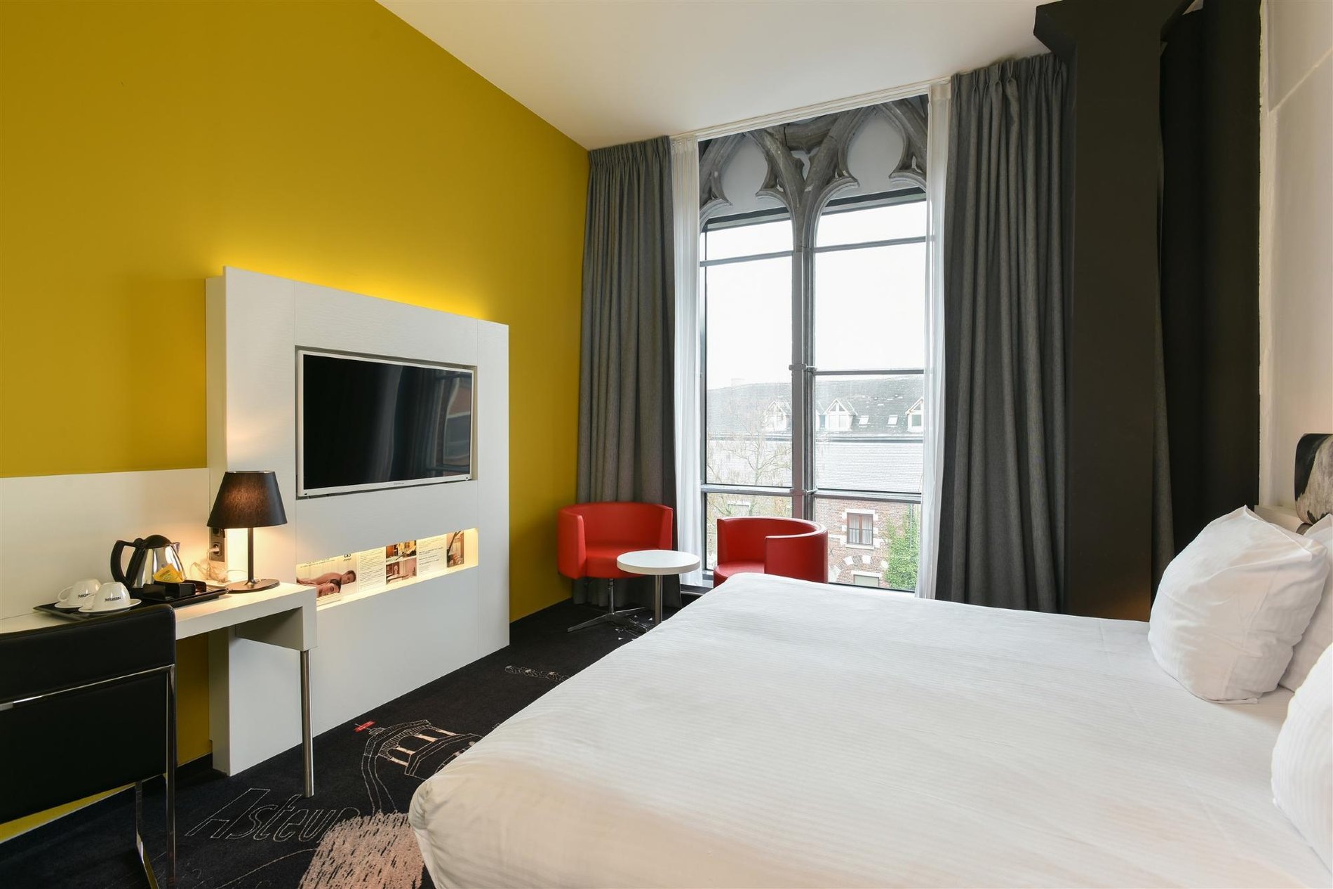 Charming Plus Zimmer mit Minibar und hellem Fenster.