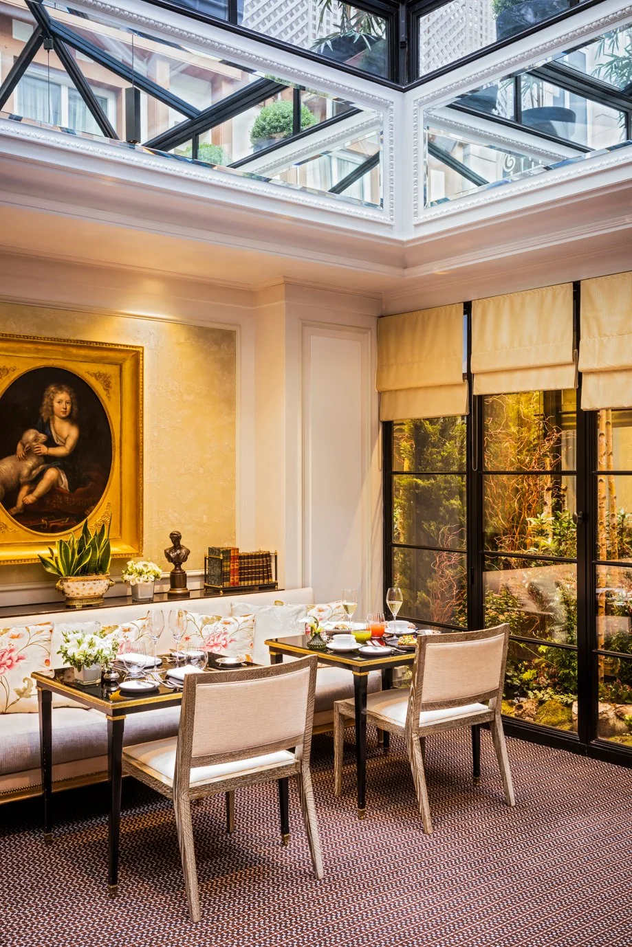 Table dressée sous la verrière du restaurant Les Confidences à l’Hôtel San Régis, pour un moment gourmand à Paris 8.
