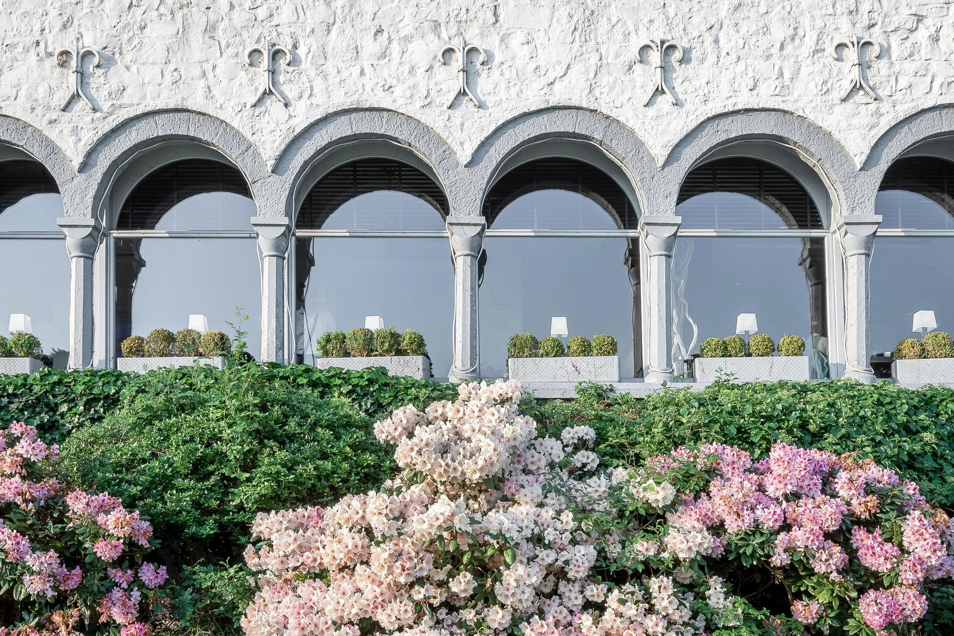 Blumengarten und elegante Bögen an der Fassade des Martin's Château du Lac.