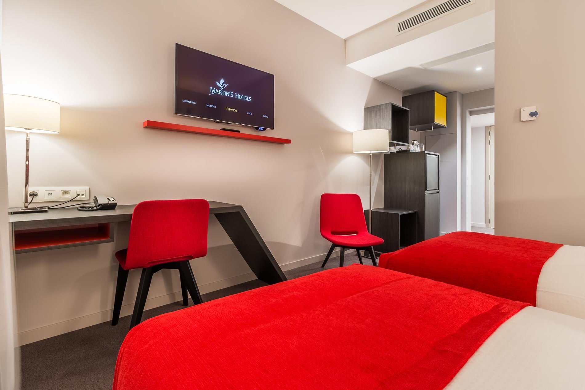 Room at Martin's Red with a desk area, red chair, and wall-mounted TV.