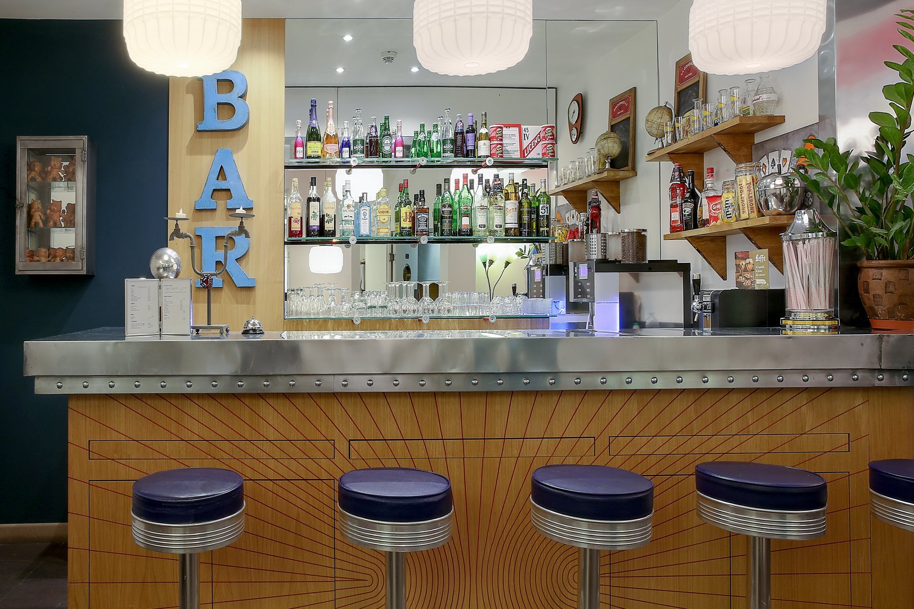 Bar rétro de l’Hôtel Aulivia Opéra avec tabourets et étagères garnies de bouteilles