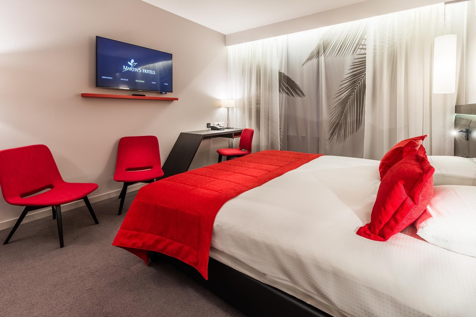 Modern room at Martin's Red with a double bed, red armchairs, and large windows.