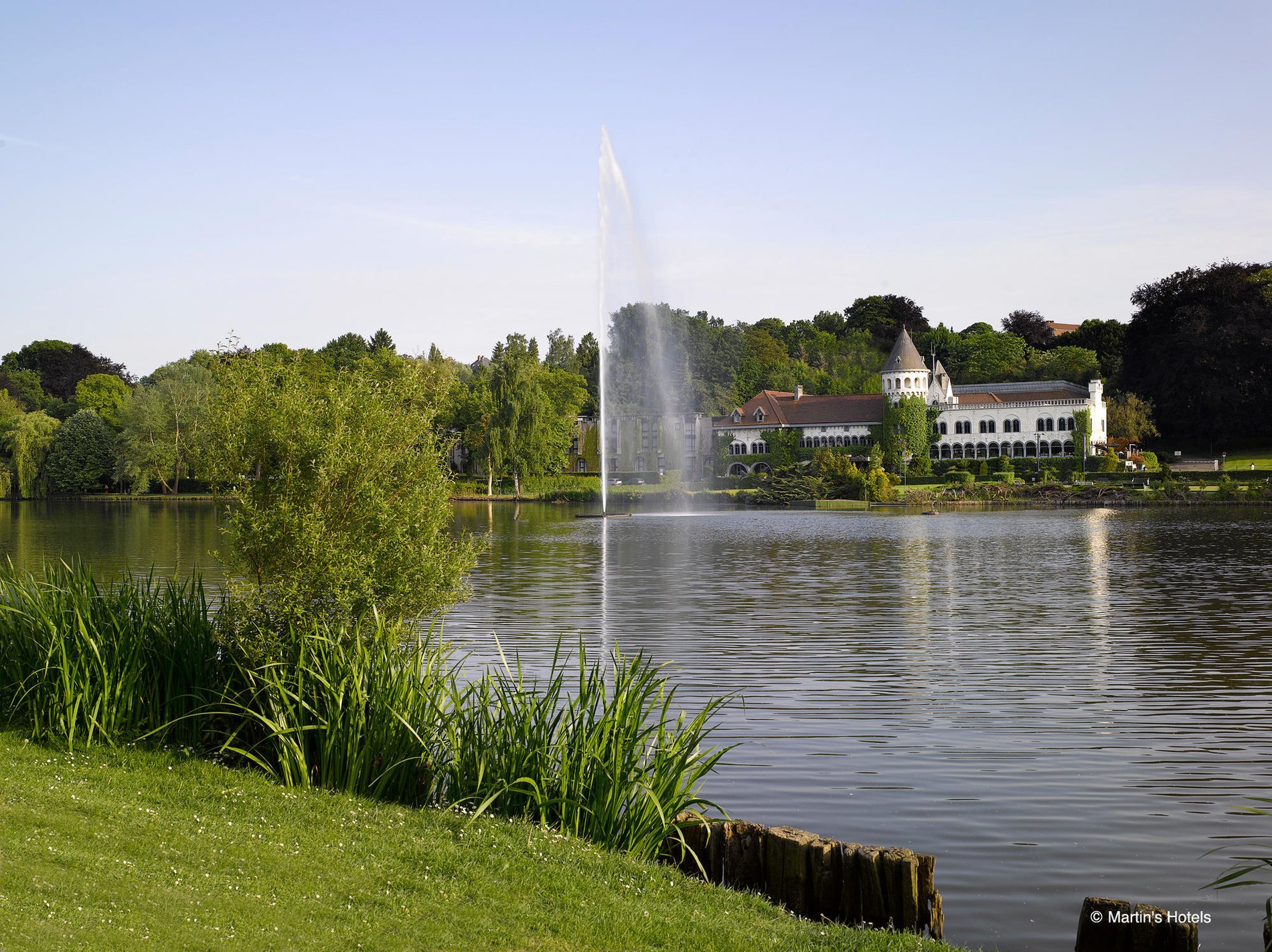 View of the lake with a fountain and greenery from Martin's Château du Lac.