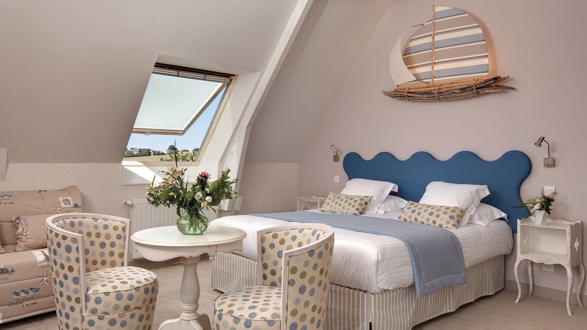 Chambre Supérieure de l'Hôtel La Ramade avec coin salon et décoration marine, symbolisant un espace de détente additionnel.