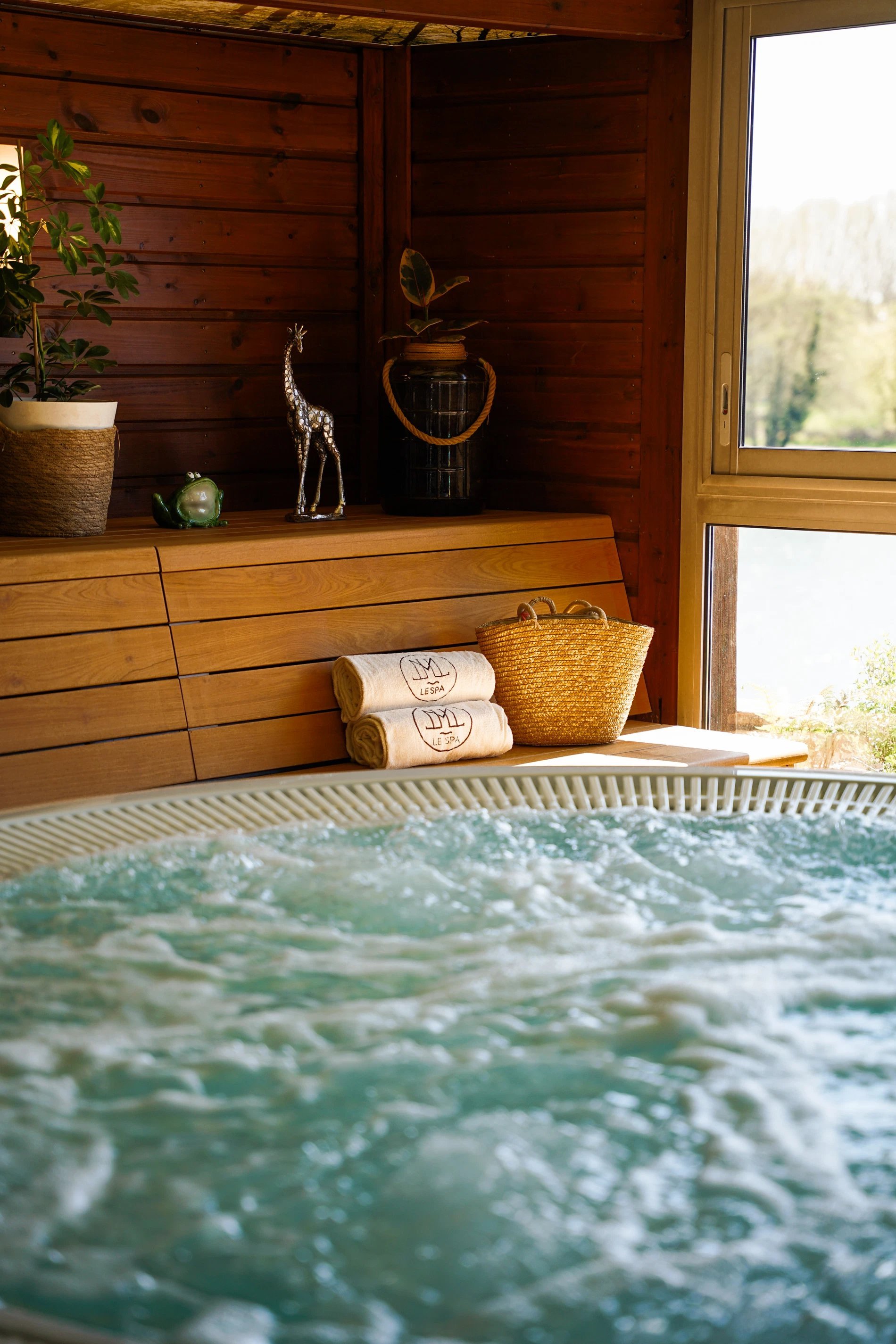 Indoor jacuzzi at La Côte Saint Jacques spa with whirlpool bath, wooden walls and window