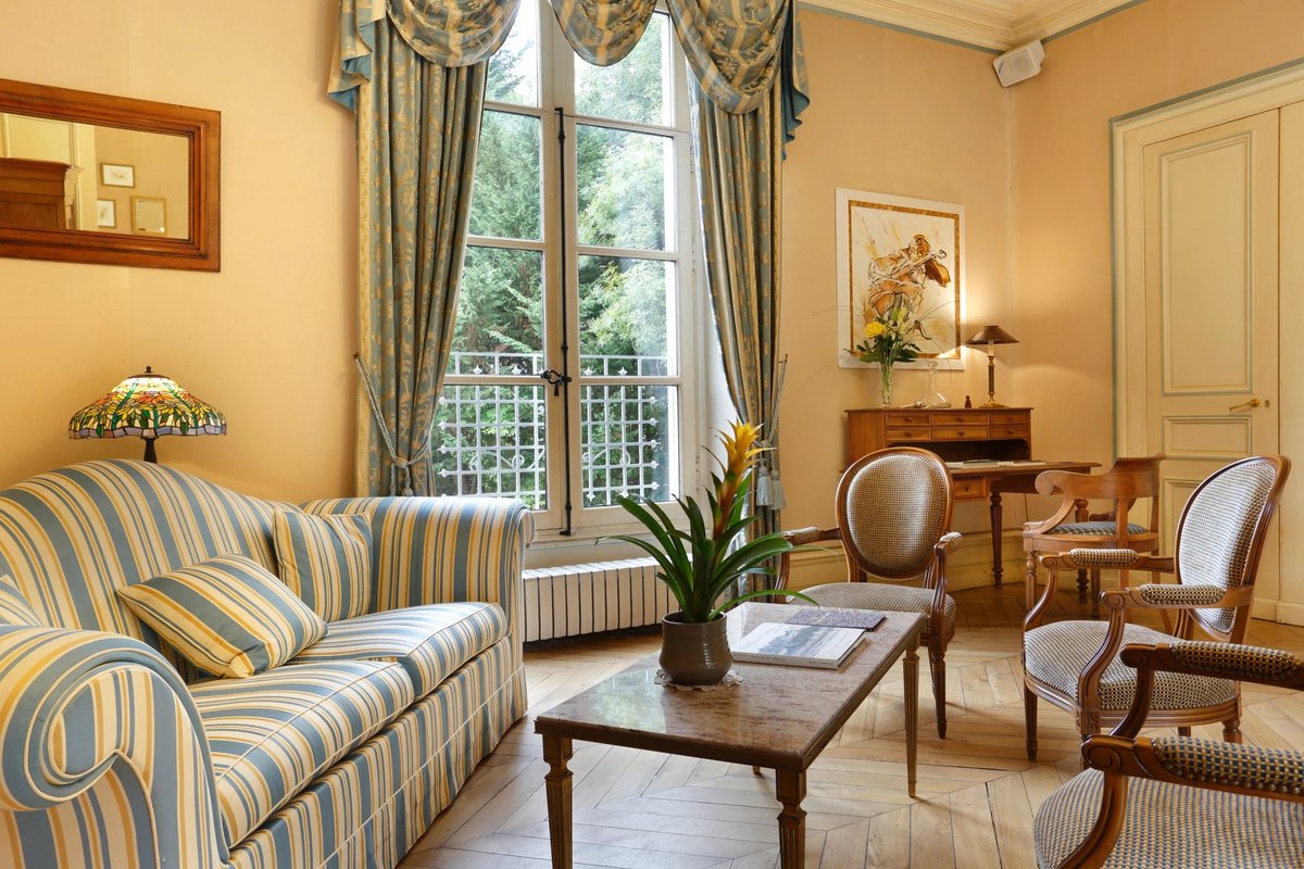 Château de la Rozelle, Salon élégant avec canapé rayé et meubles en bois dans un hôtel à La Rochelle.
