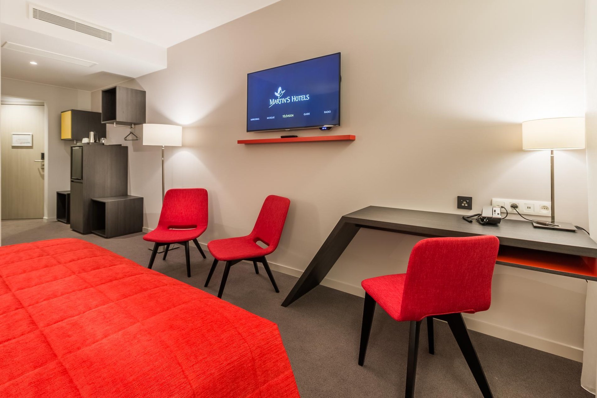 Room at Martin's Red with a double bed, desk area, wall-mounted TV, and red decor.